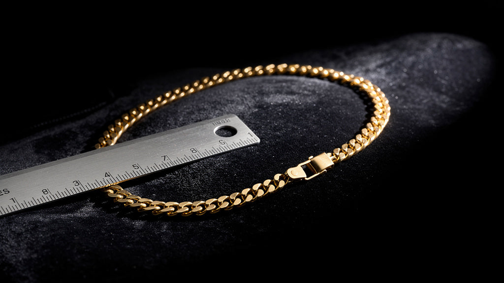 Gold chain necklace with a shortener clip and ruler showing how to shorten a necklace chain