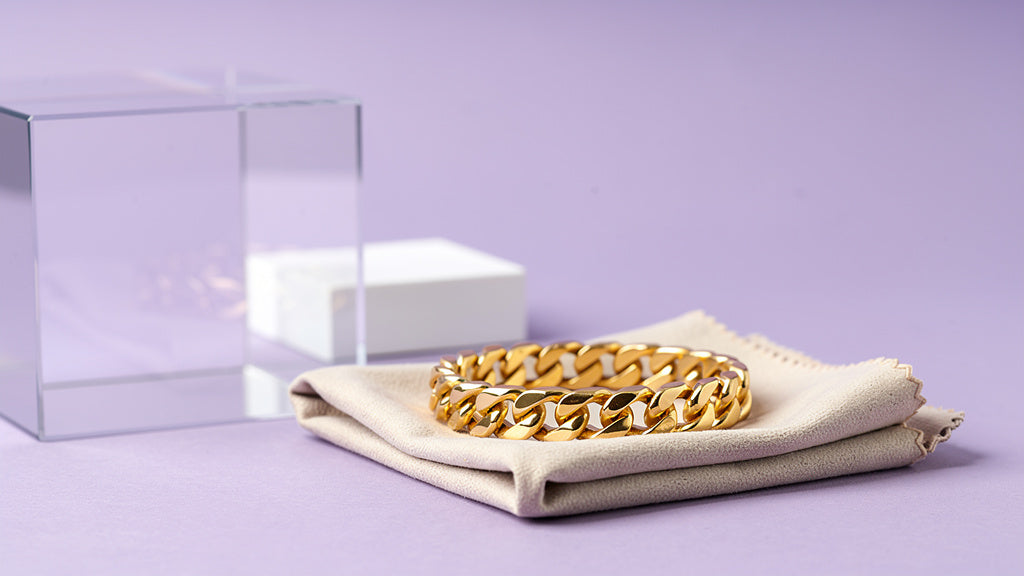 14k gold chain bracelet half polished next to a polishing cloth, showing tarnish
