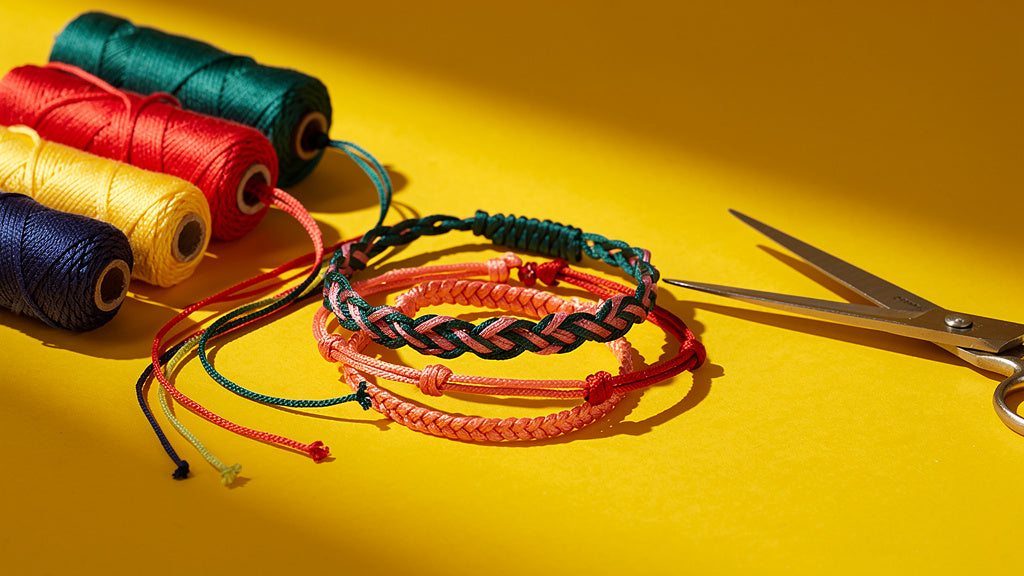 Finished braided and knotted string bracelets with embroidery floss spools