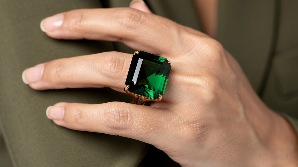 Green emerald gemstone in a gold ring, showing natural emerald color