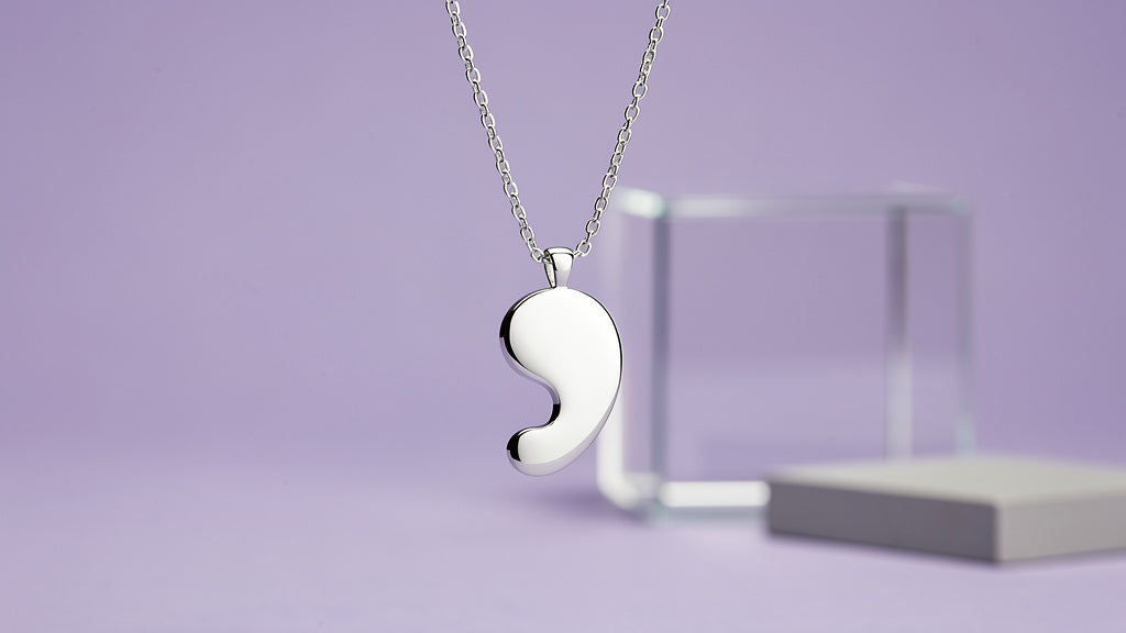 Semicolon necklace pendant hanging on a fine gold chain