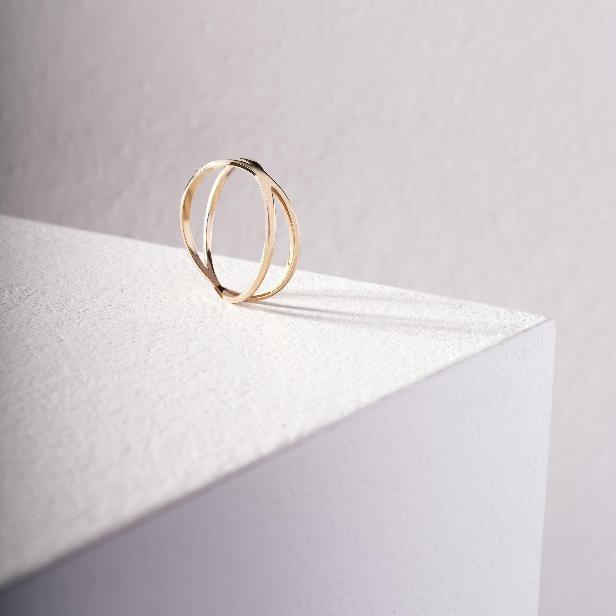 Minimalist gold ring with double band design on white textured surface