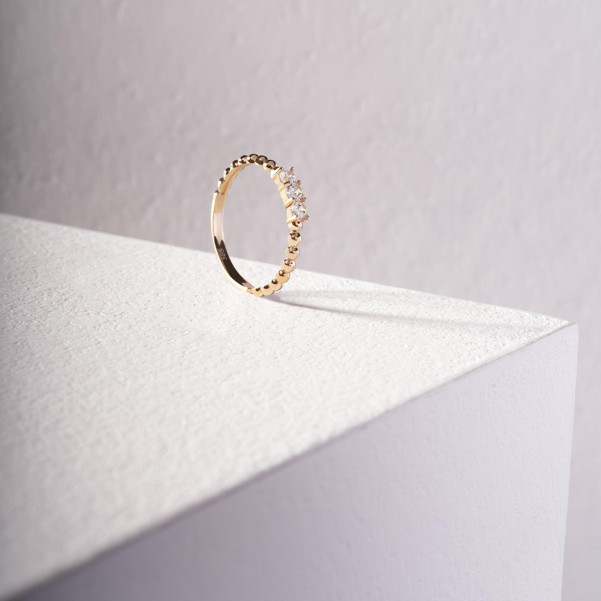 Gold ring with round and baguette diamonds on a textured white surface