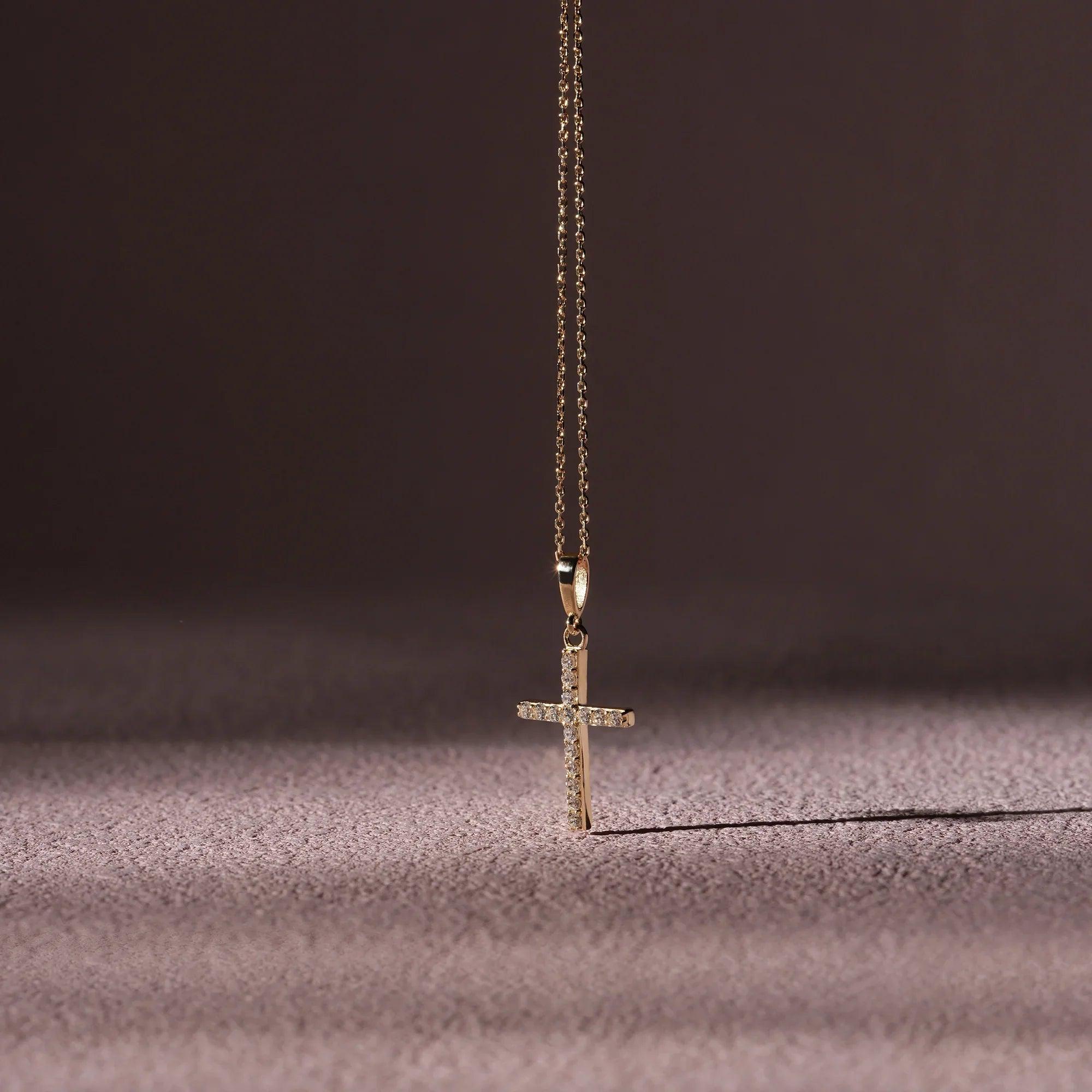 Gold cross pendant necklace with small diamonds on a delicate chain, elegant jewelry