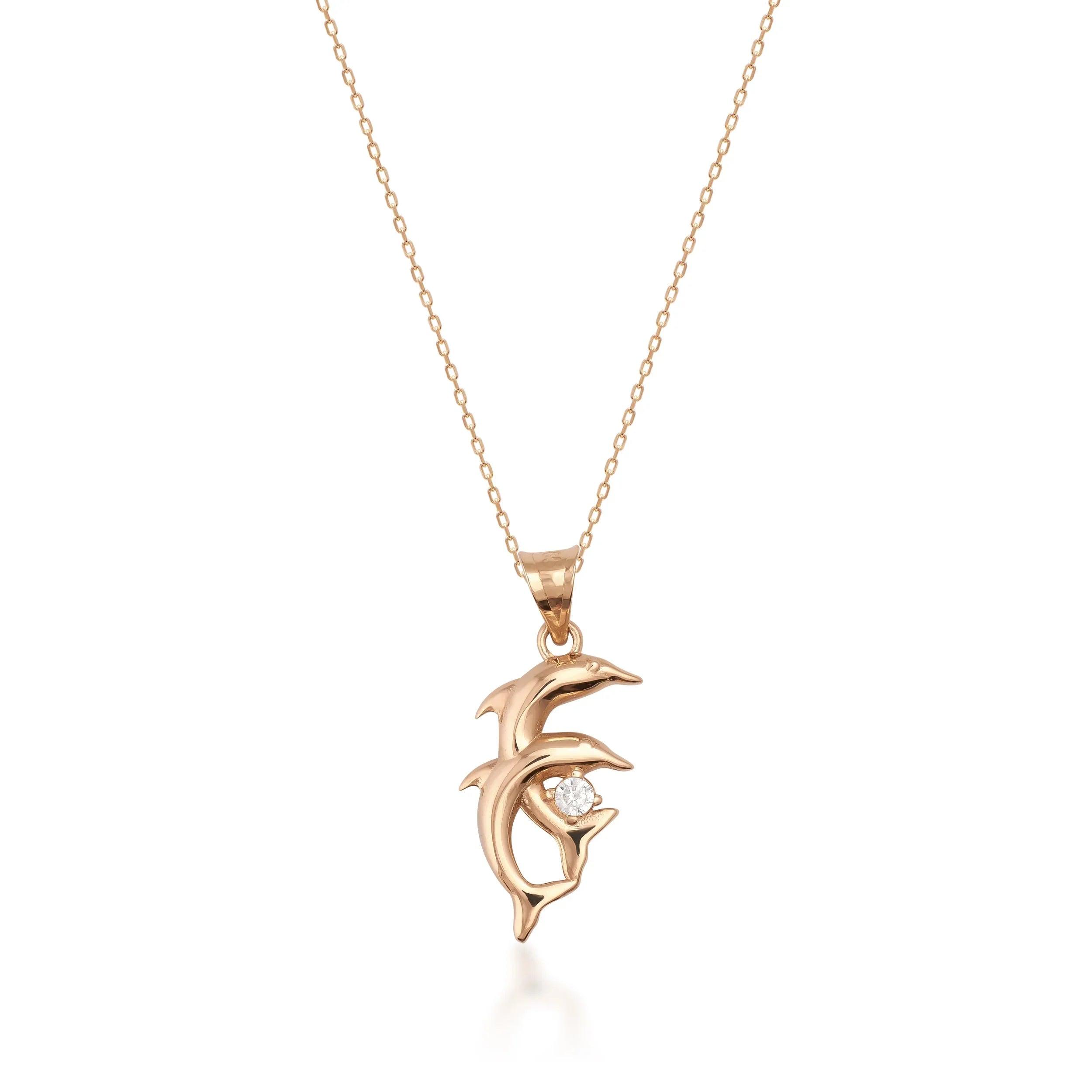 Gold dolphin pendant necklace with clear gemstone on fine chain, minimal white background