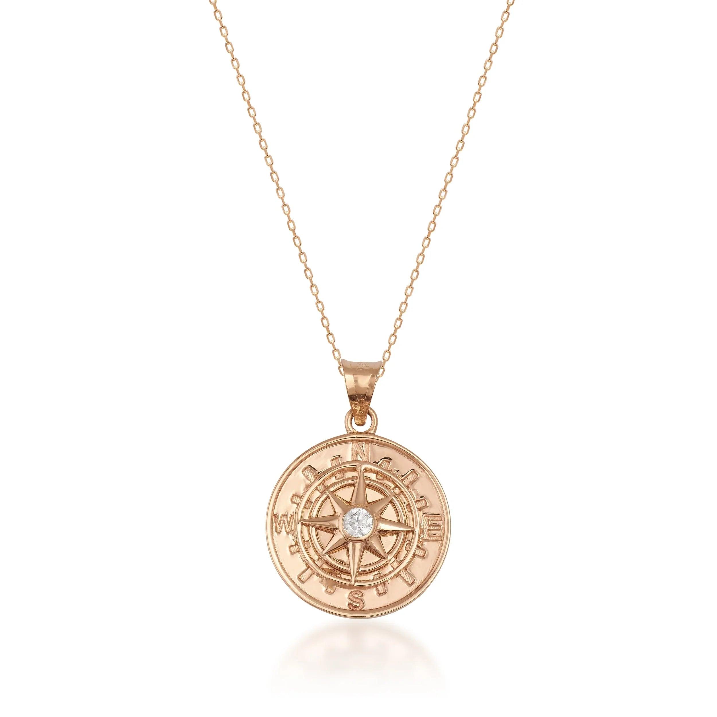 Gold compass pendant necklace with diamond center on fine gold chain, white background