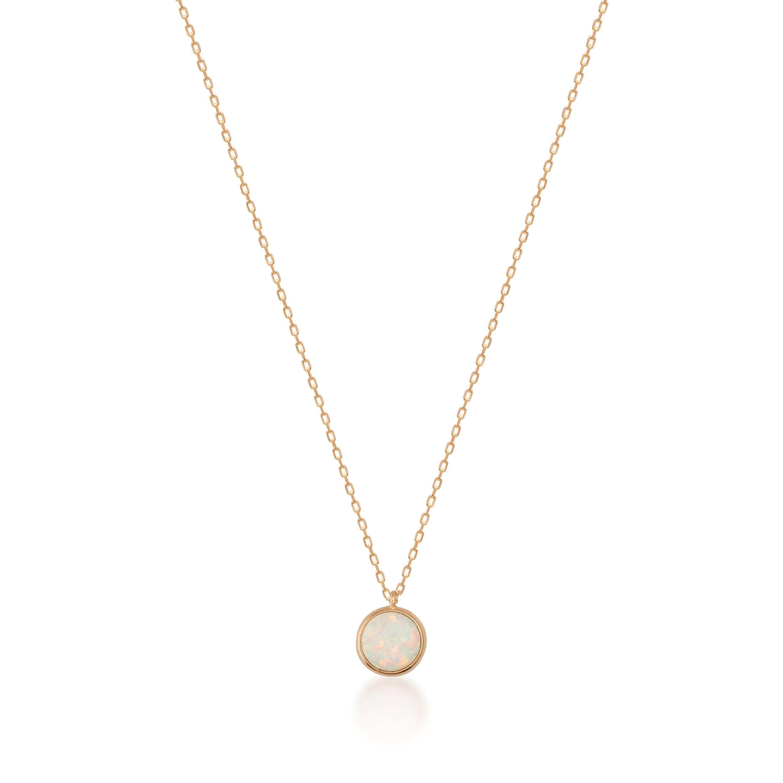 Gold chain necklace with round opal gemstone pendant on white background