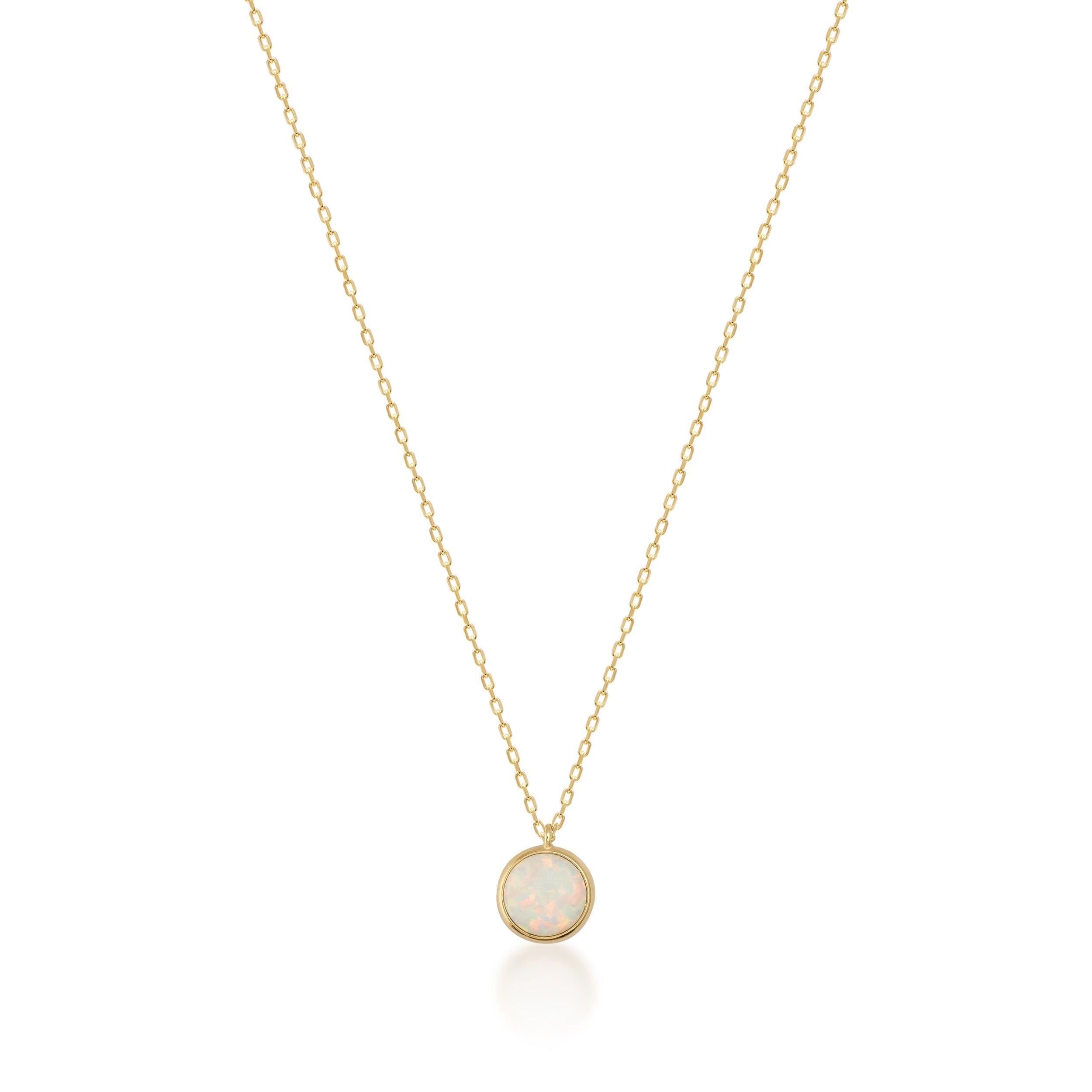 Gold necklace with round opal pendant on a plain white background