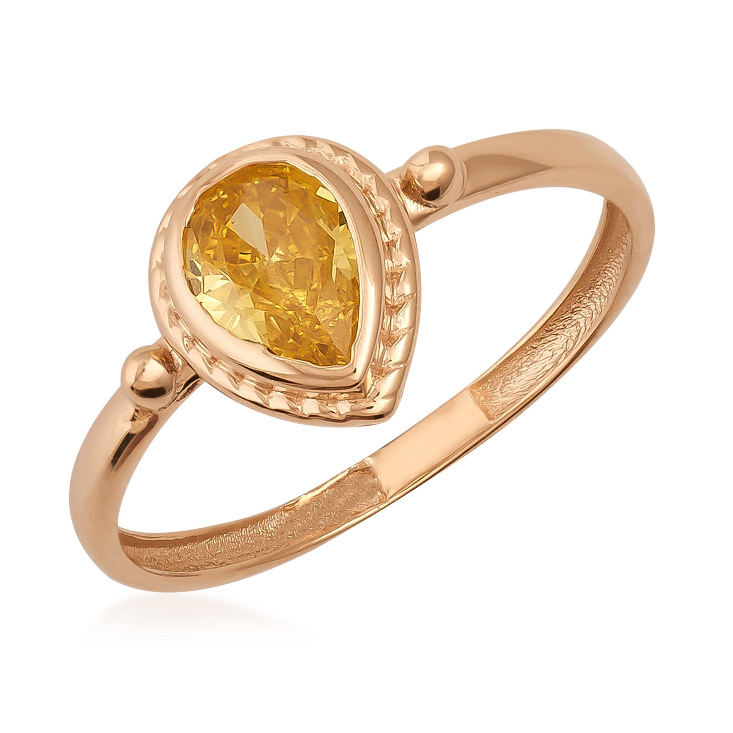 Gold ring with teardrop-shaped yellow gemstone and decorative bezel setting