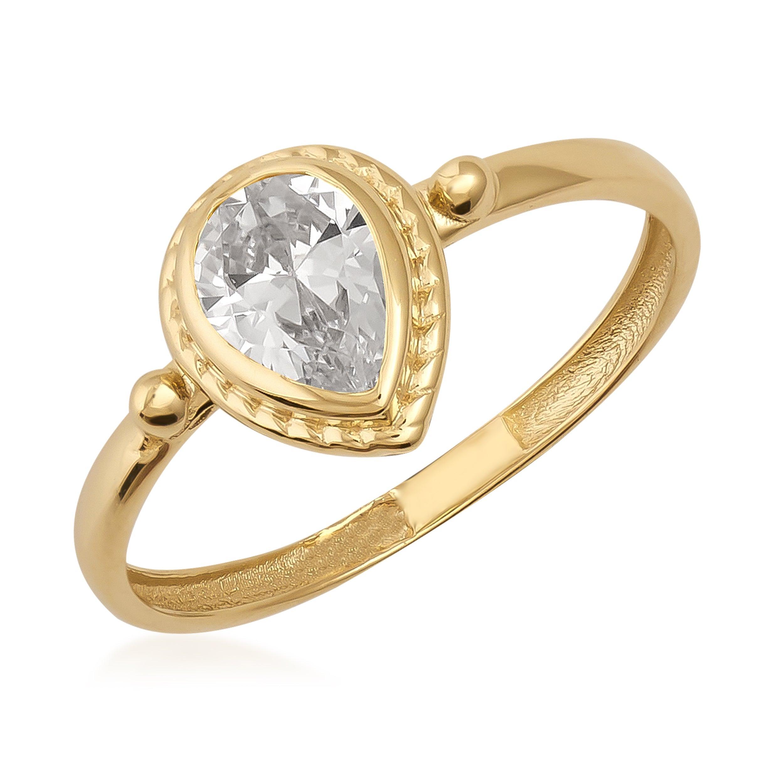 Gold ring with pear-shaped clear gemstone and ornate detailing on the band