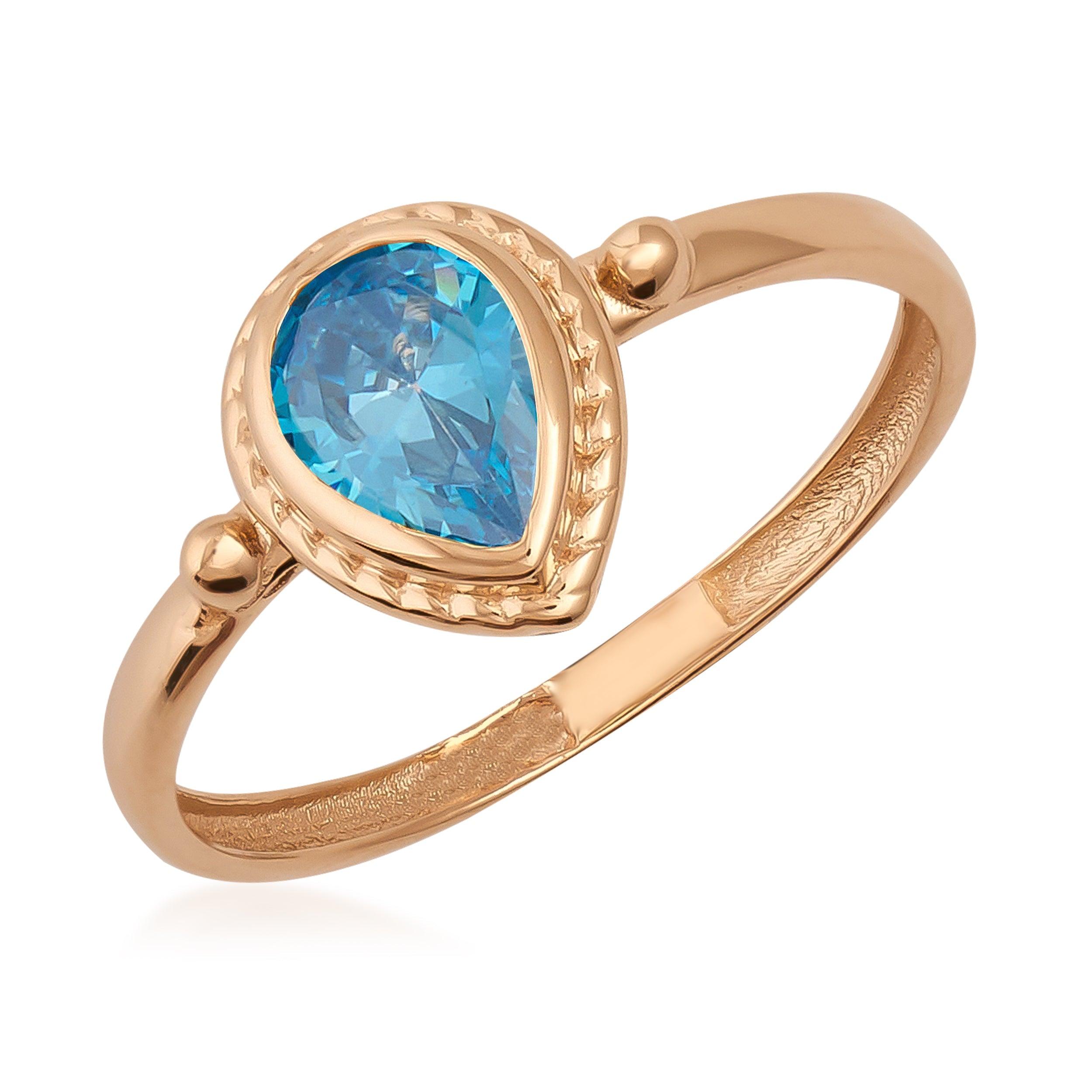Gold ring with pear-shaped blue gemstone set in a textured bezel setting
