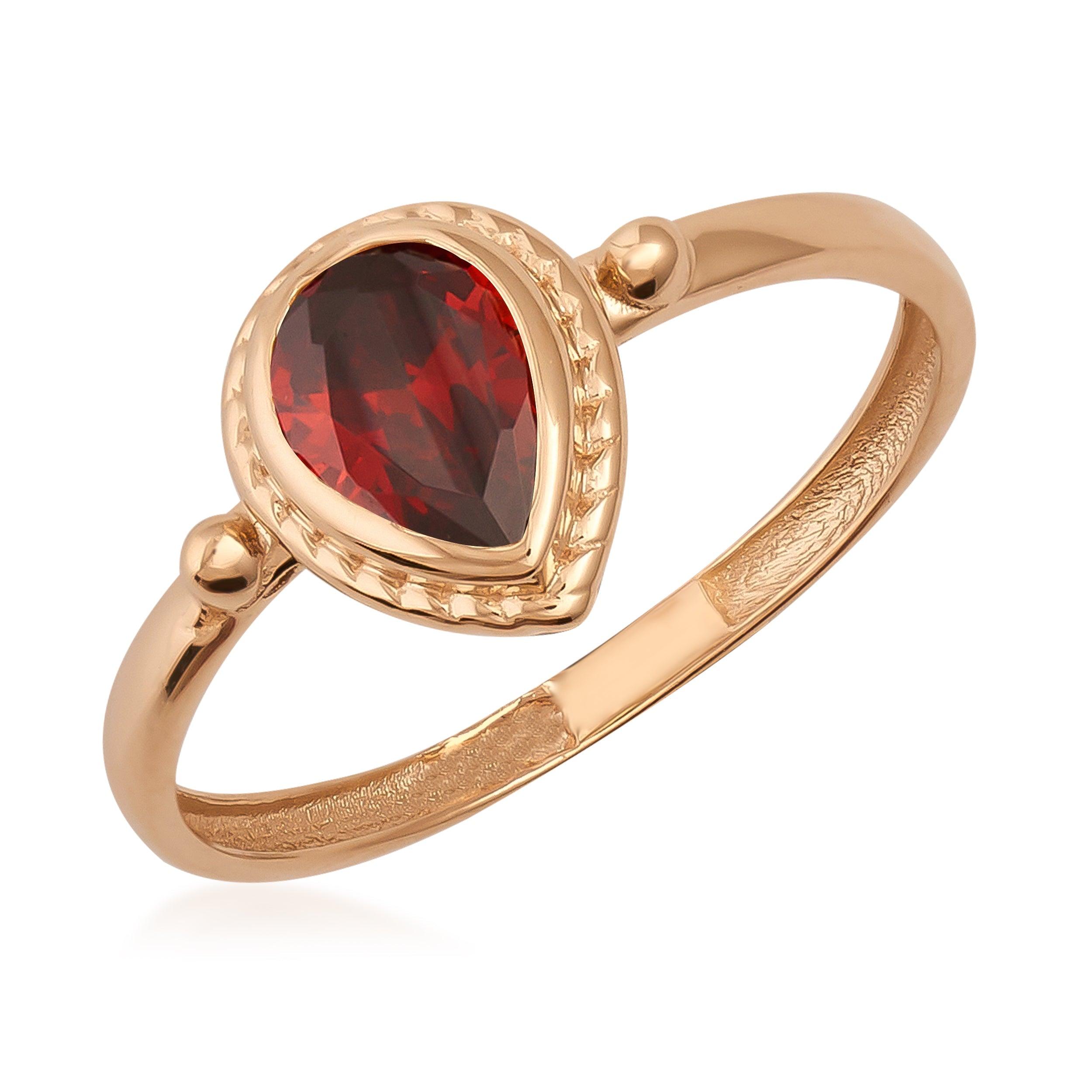Gold ring with pear-shaped red gemstone and intricate setting, fine jewelry close-up.