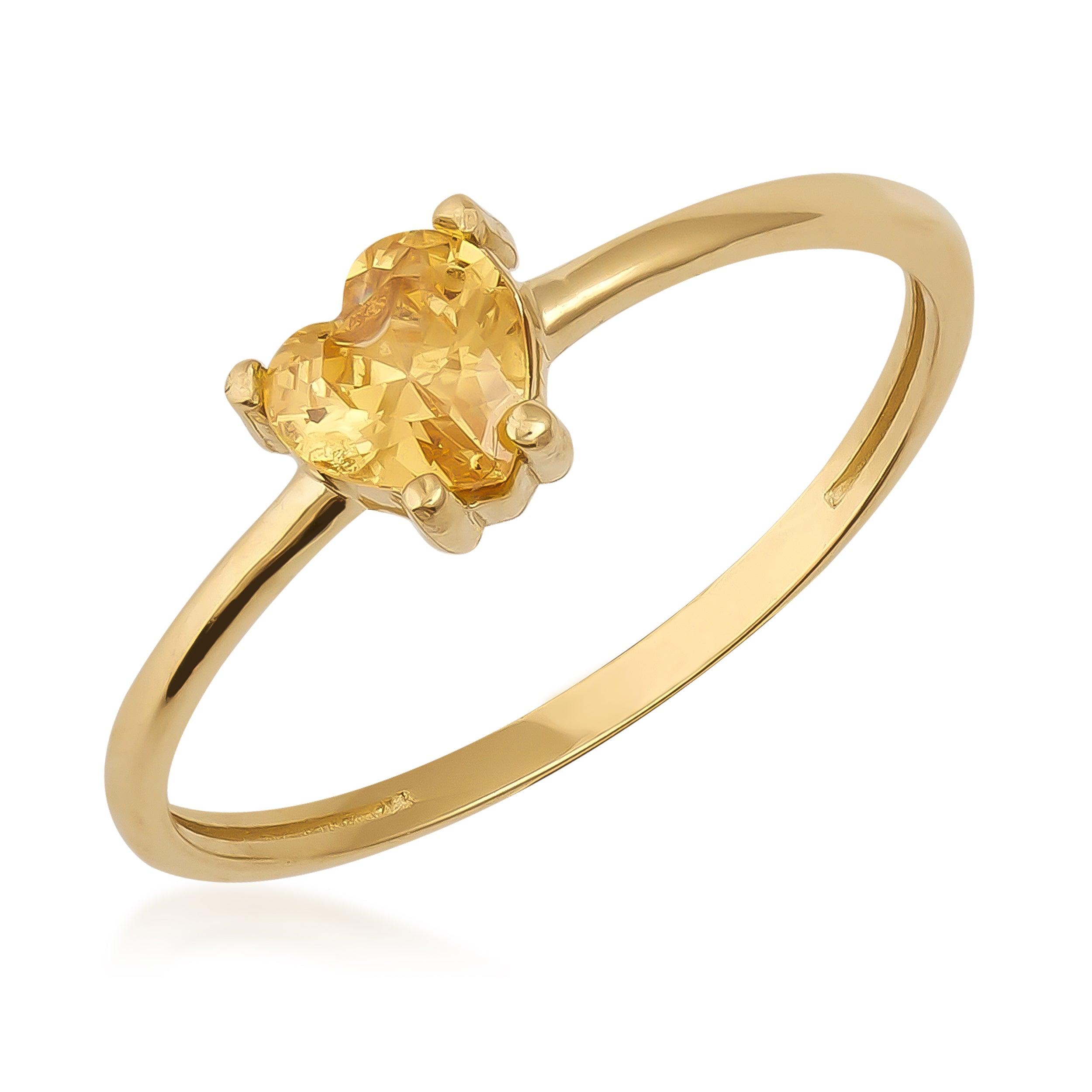 Gold ring with heart-shaped yellow gemstone on a plain white background