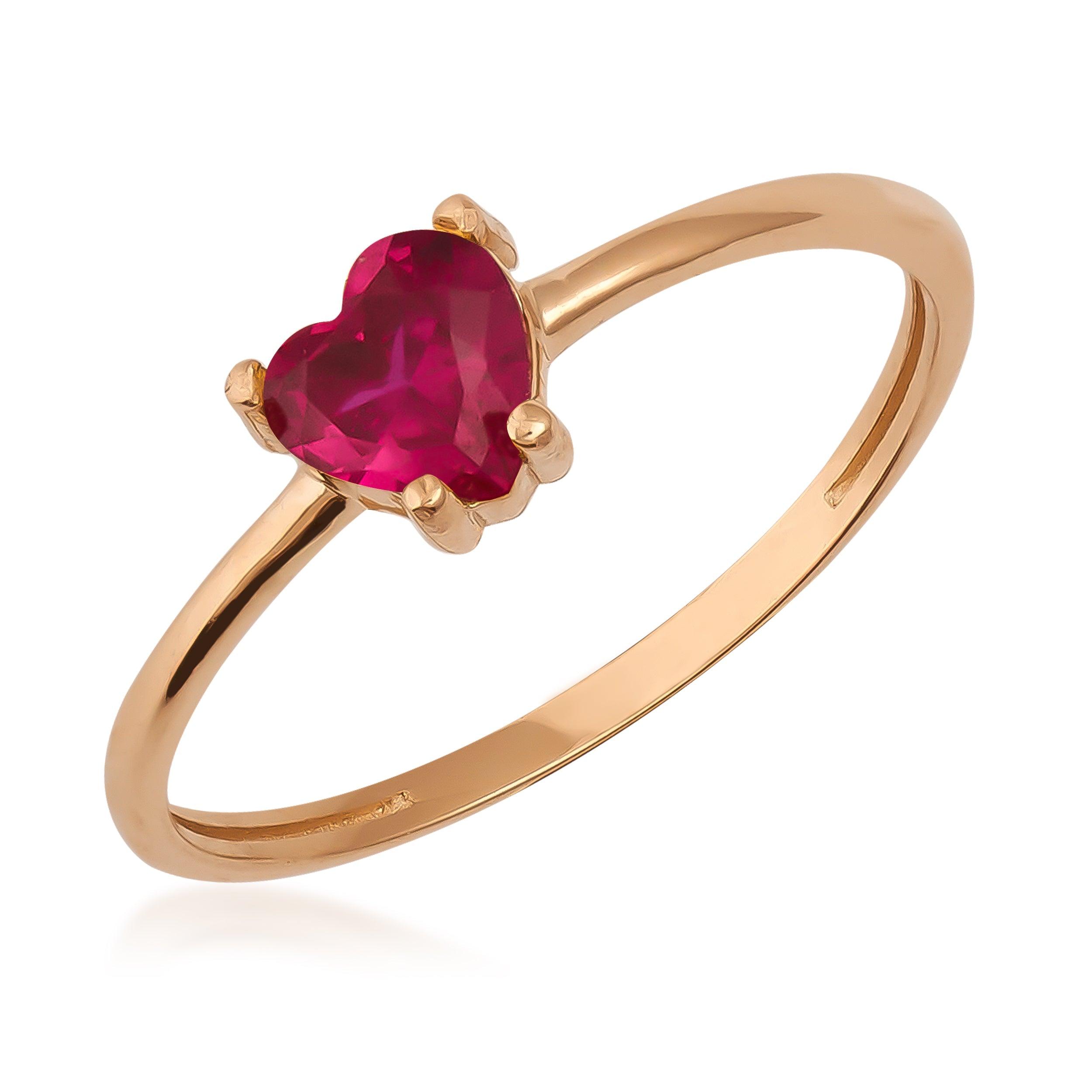 Gold ring with heart-shaped red gemstone on white background, elegant jewelry design