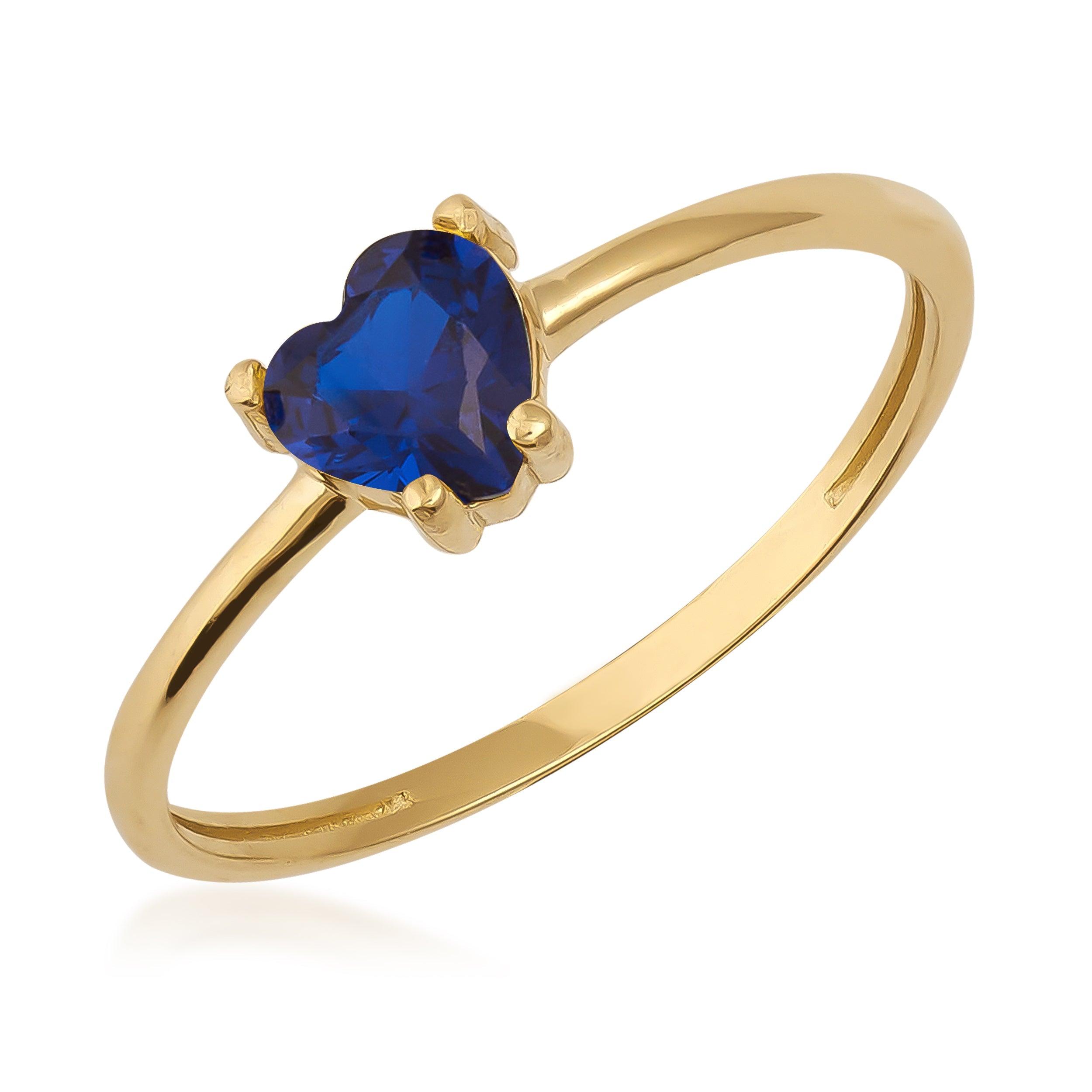 Gold ring with heart-shaped blue sapphire gemstone on white background