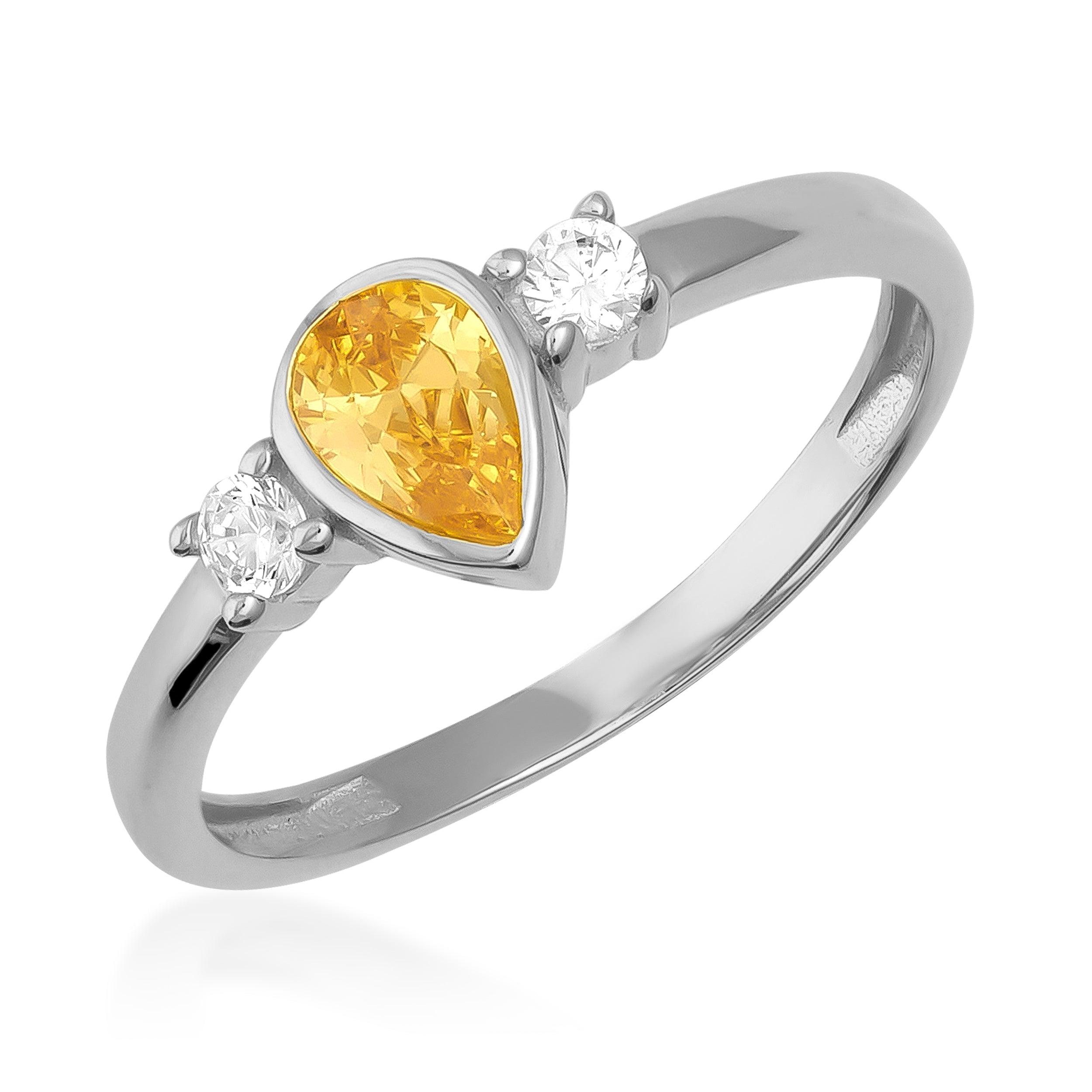 Gold ring with pear-shaped yellow gemstone and two round white stones on a white background