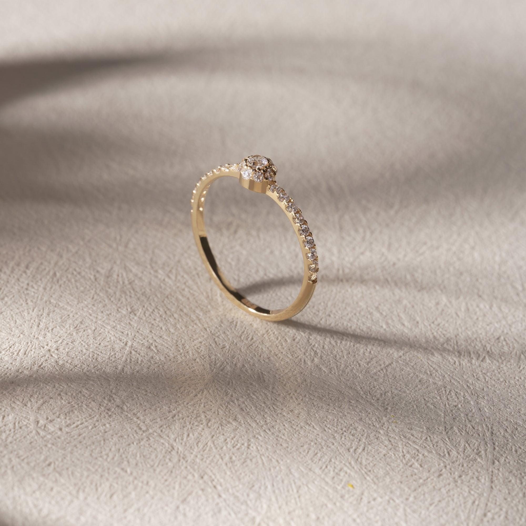 Gold diamond ring with pavé band on textured neutral background
