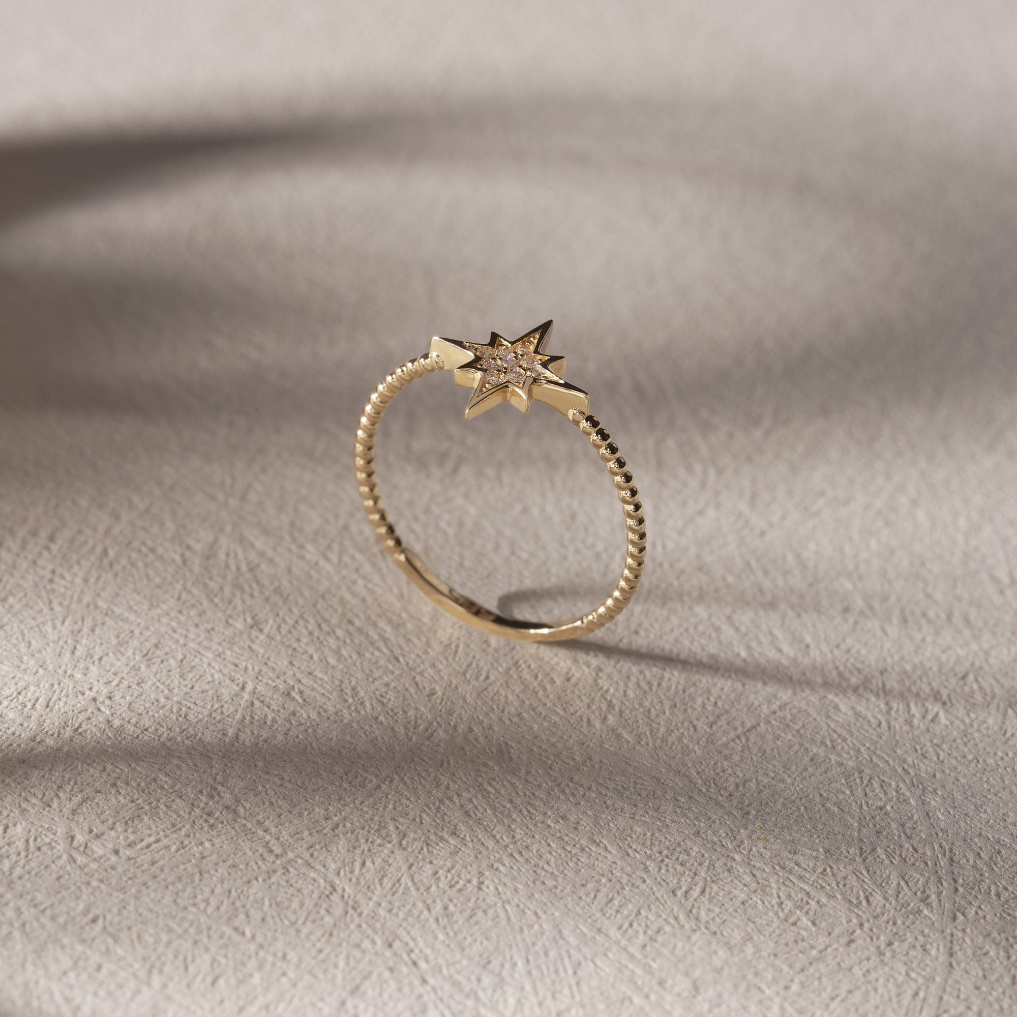 Gold ring with star-shaped diamond setting on textured light surface