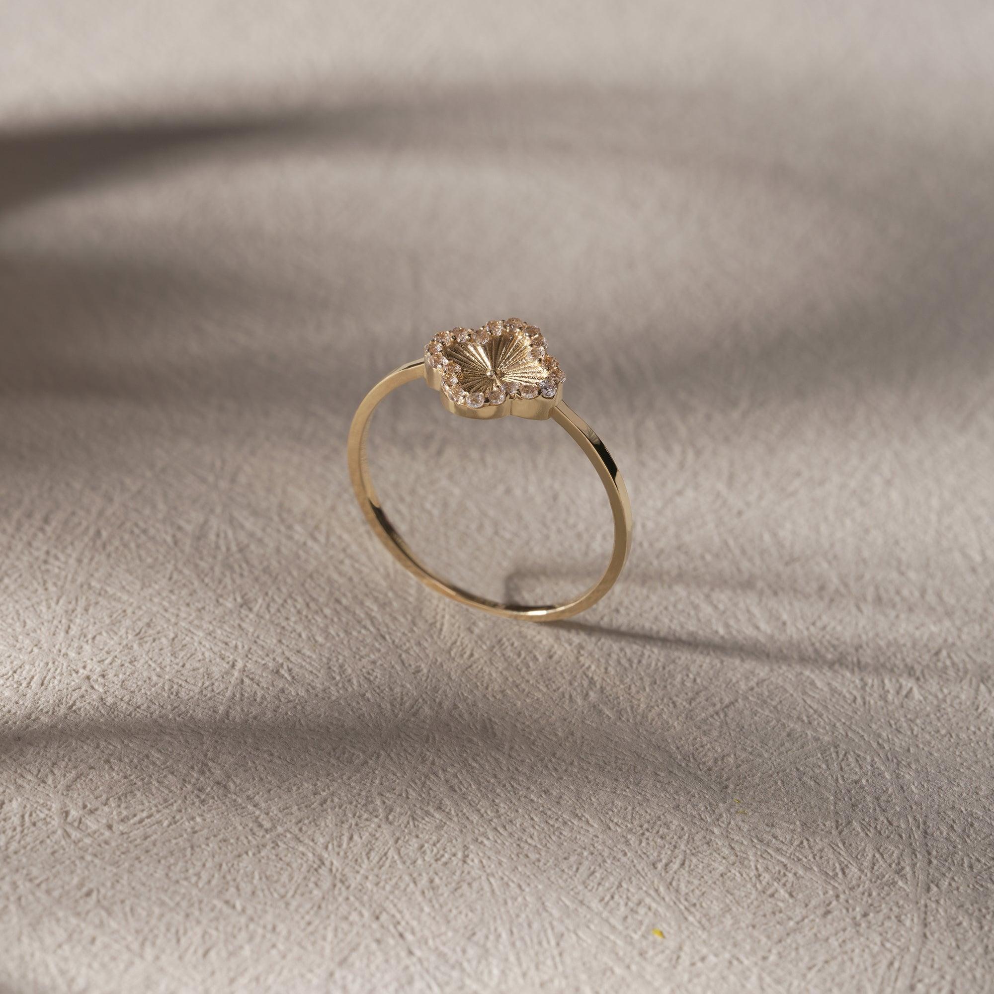 Delicate gold flower ring with textured petal design on a light background