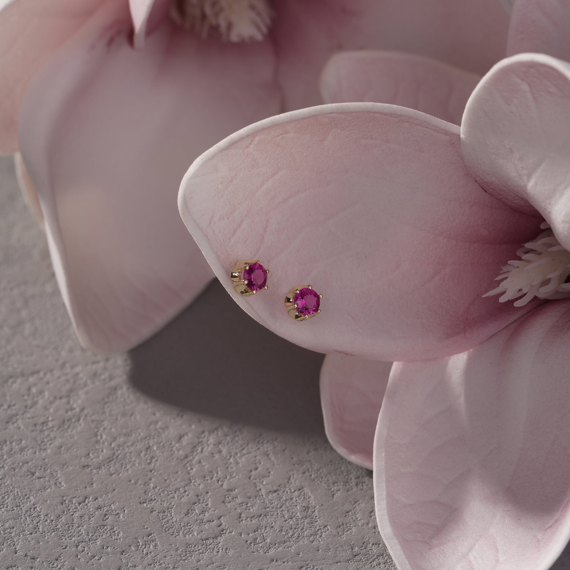 Pair of pink gemstone earrings on a pink flower