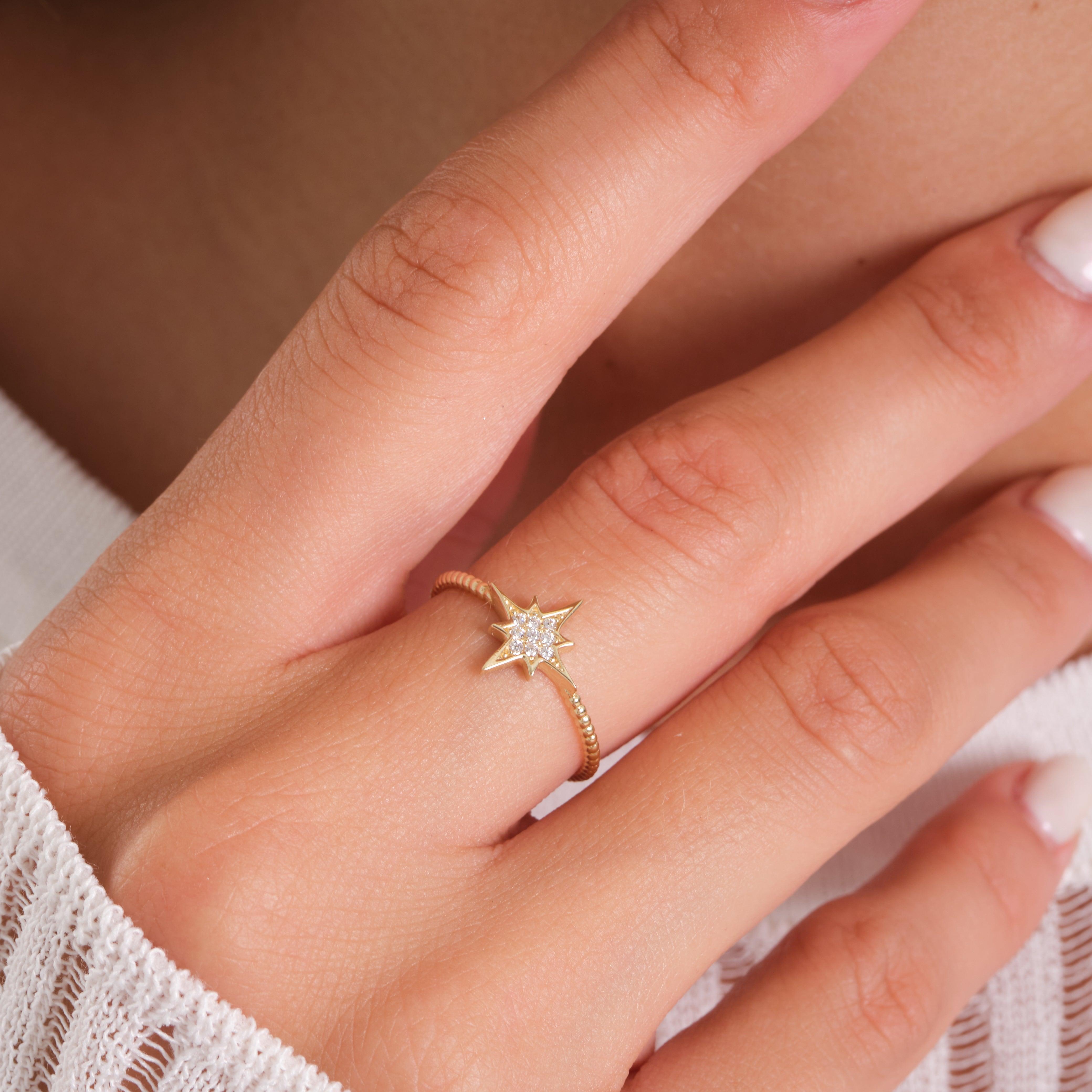 Gold star-shaped ring with sparkling stones on a woman's hand, close-up jewelry photo