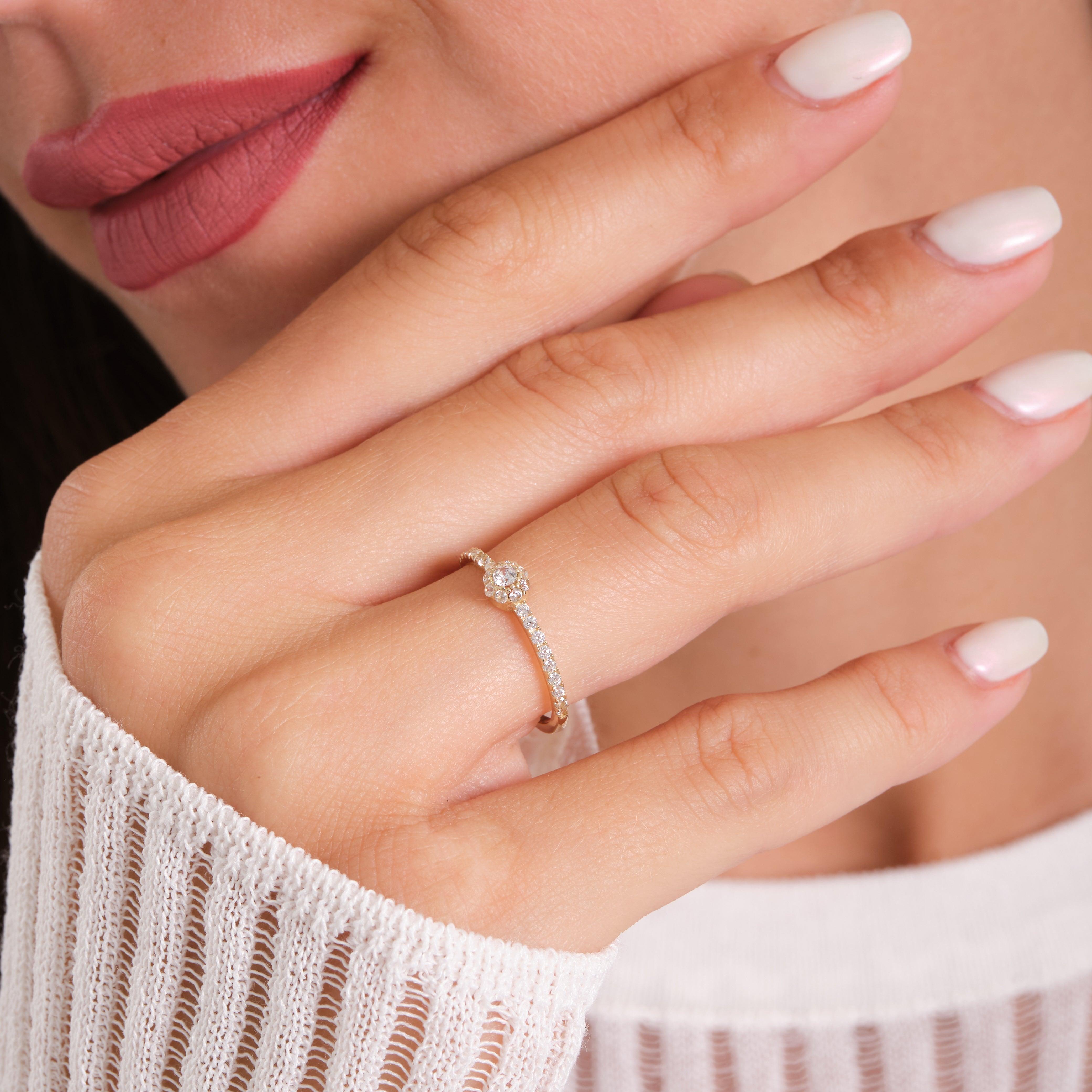 Woman wearing a delicate gold diamond ring, close-up on manicured hand and elegant jewelry