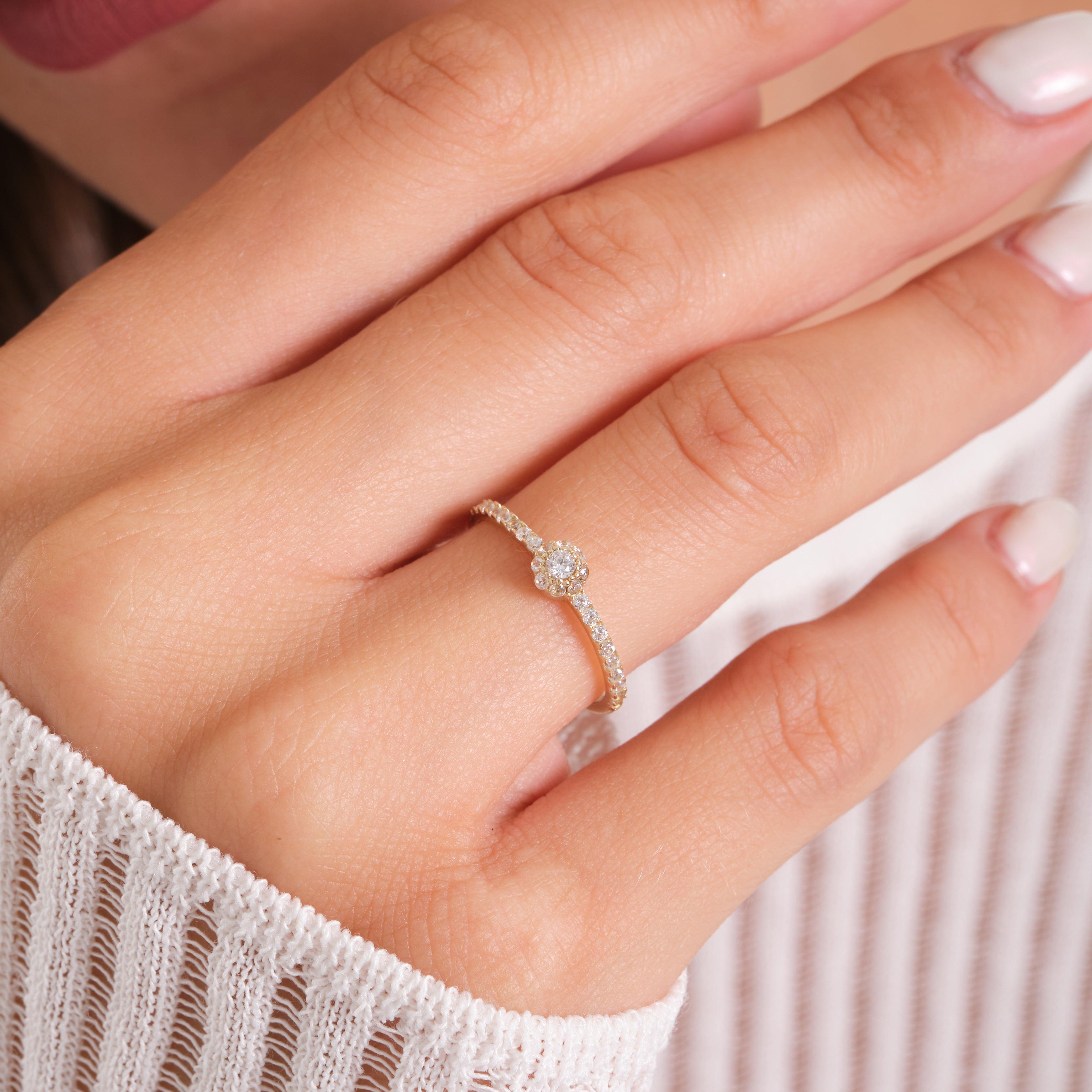Delicate gold diamond ring with a flower design on a woman's hand, close-up