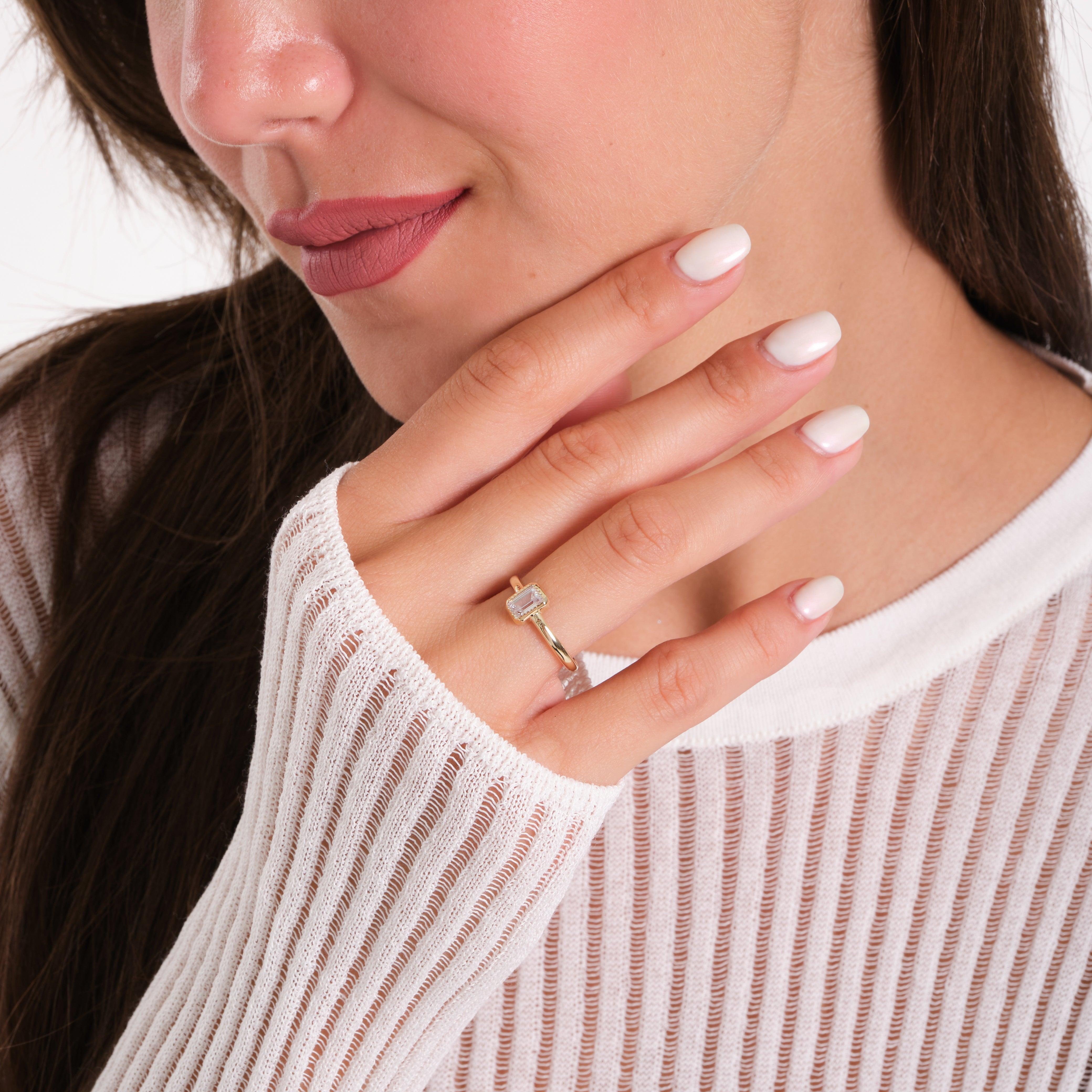 Woman wearing a gold ring with rectangular gemstone, close-up on hand and face