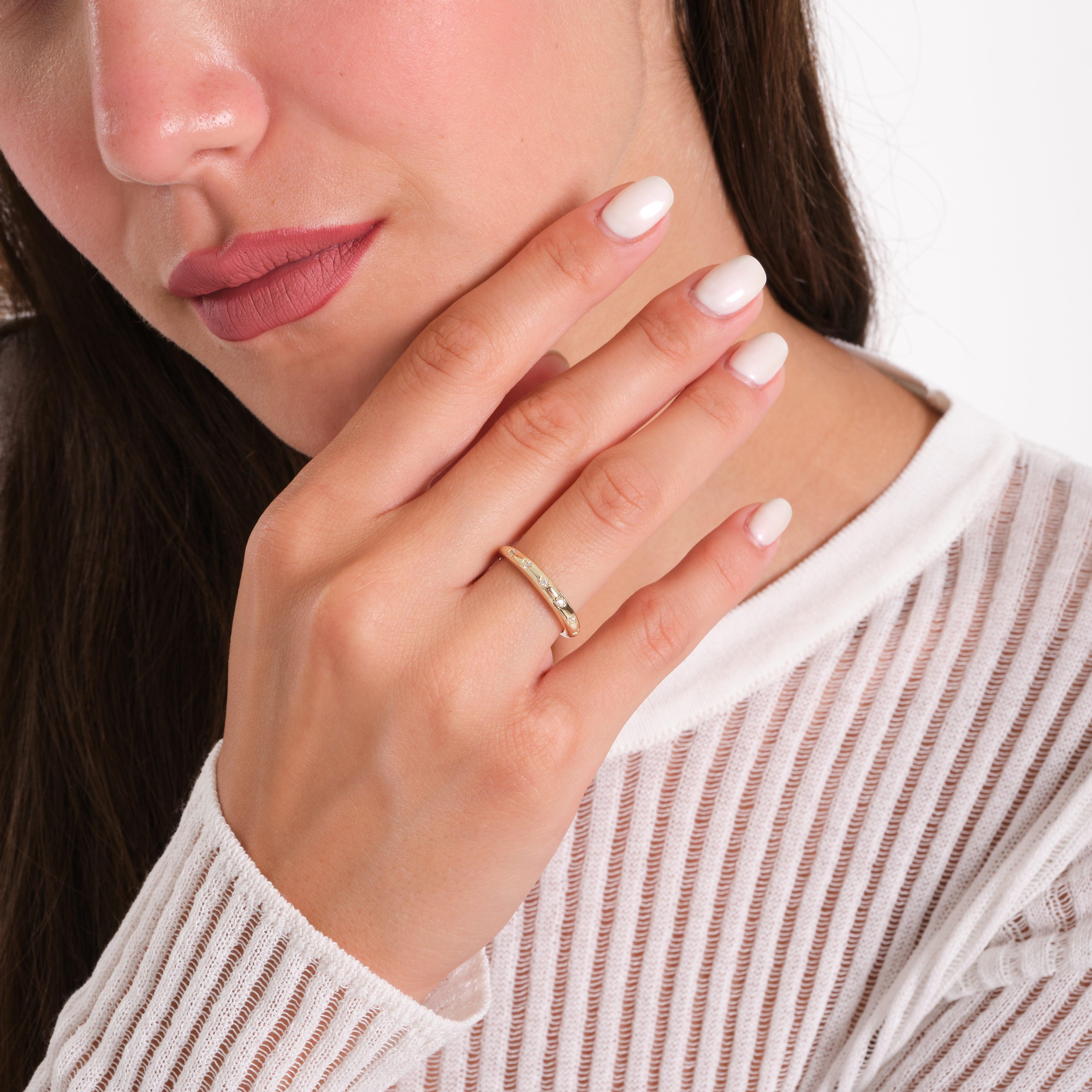 Woman wearing an elegant gold ring with gemstones, close-up hand and face, jewelry fashion