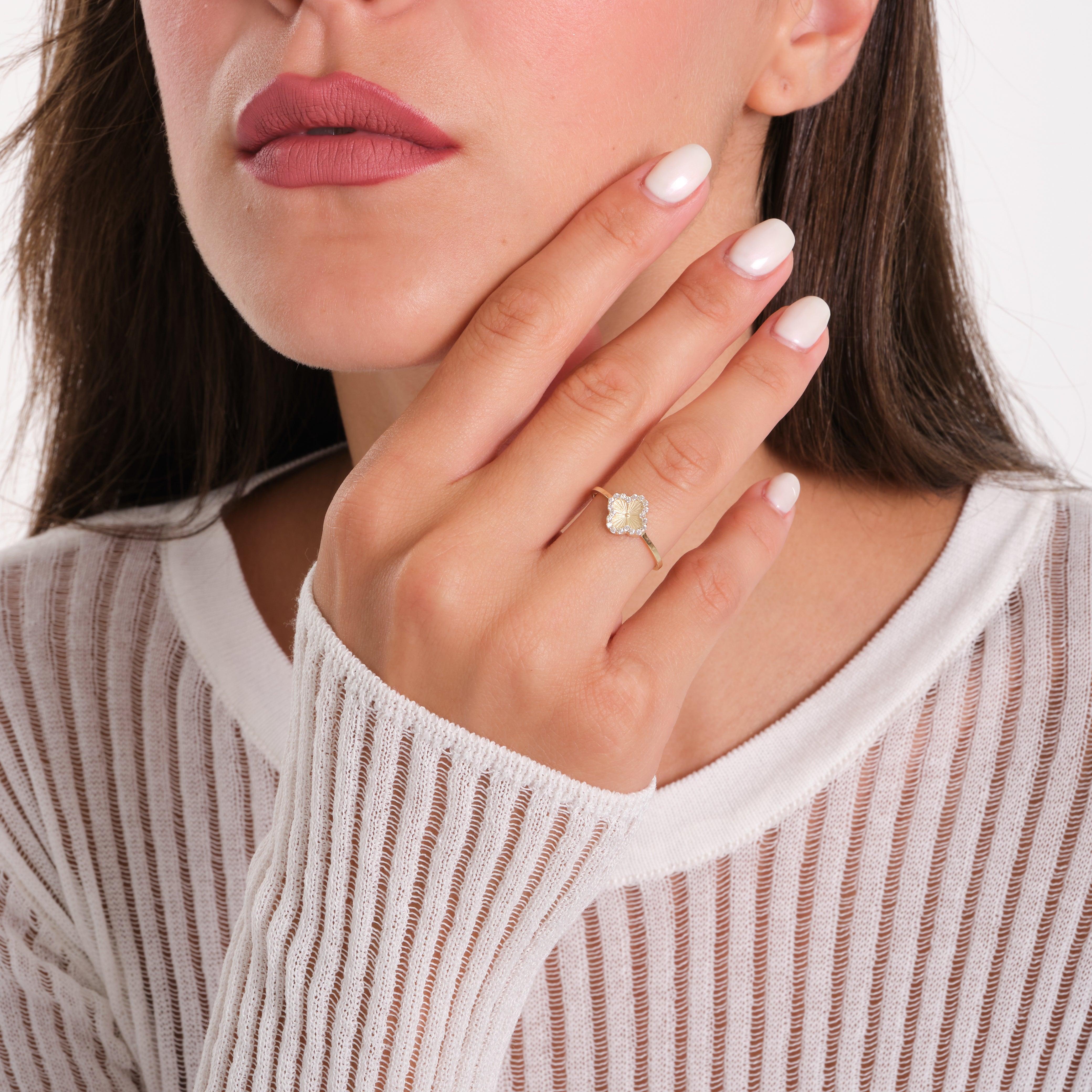 Woman wearing a gold ring with a clear gemstone, close-up on hand and face
