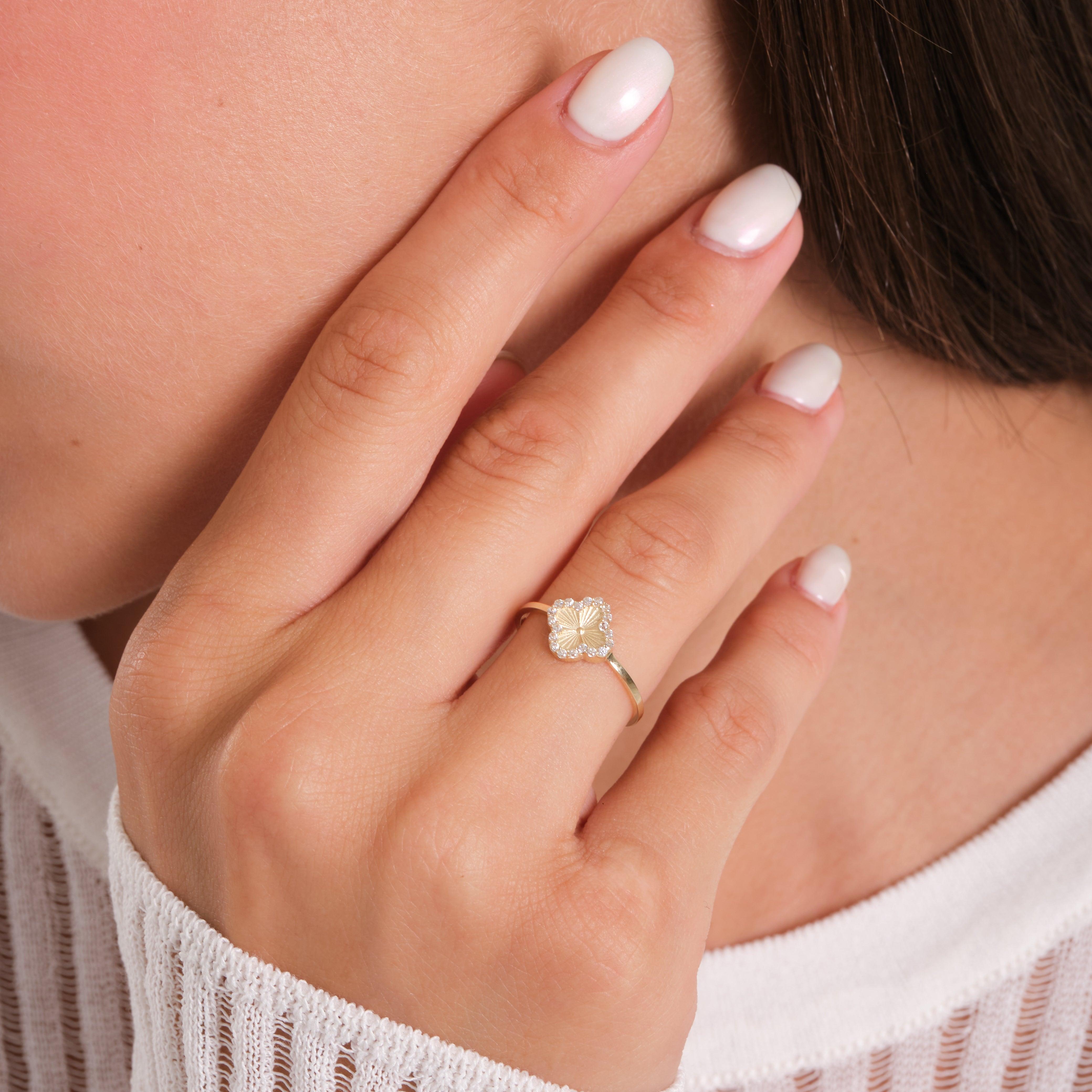 Elegant gold ring with a floral design worn on a manicured hand