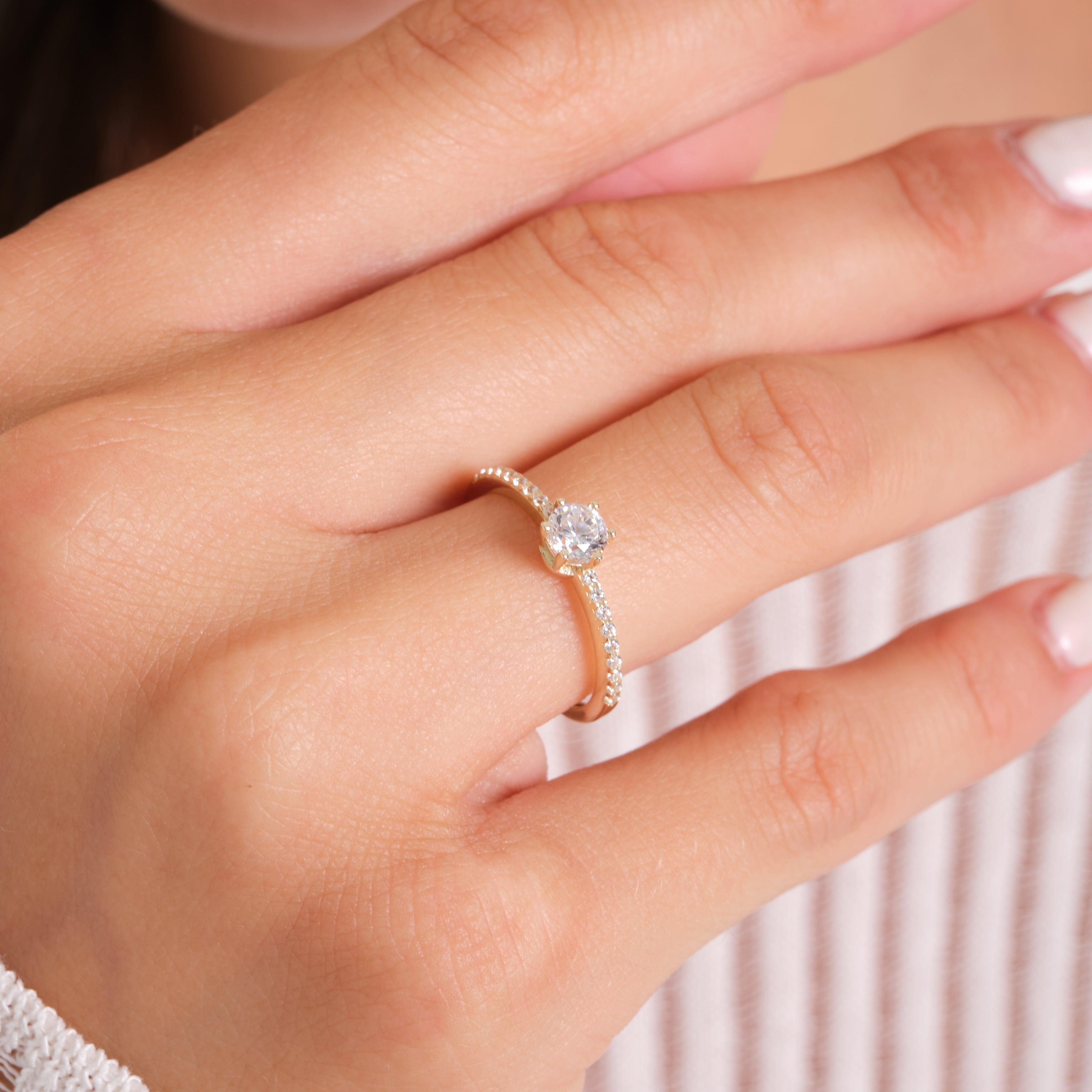 Woman wearing a gold diamond engagement ring with a pavé band on her finger