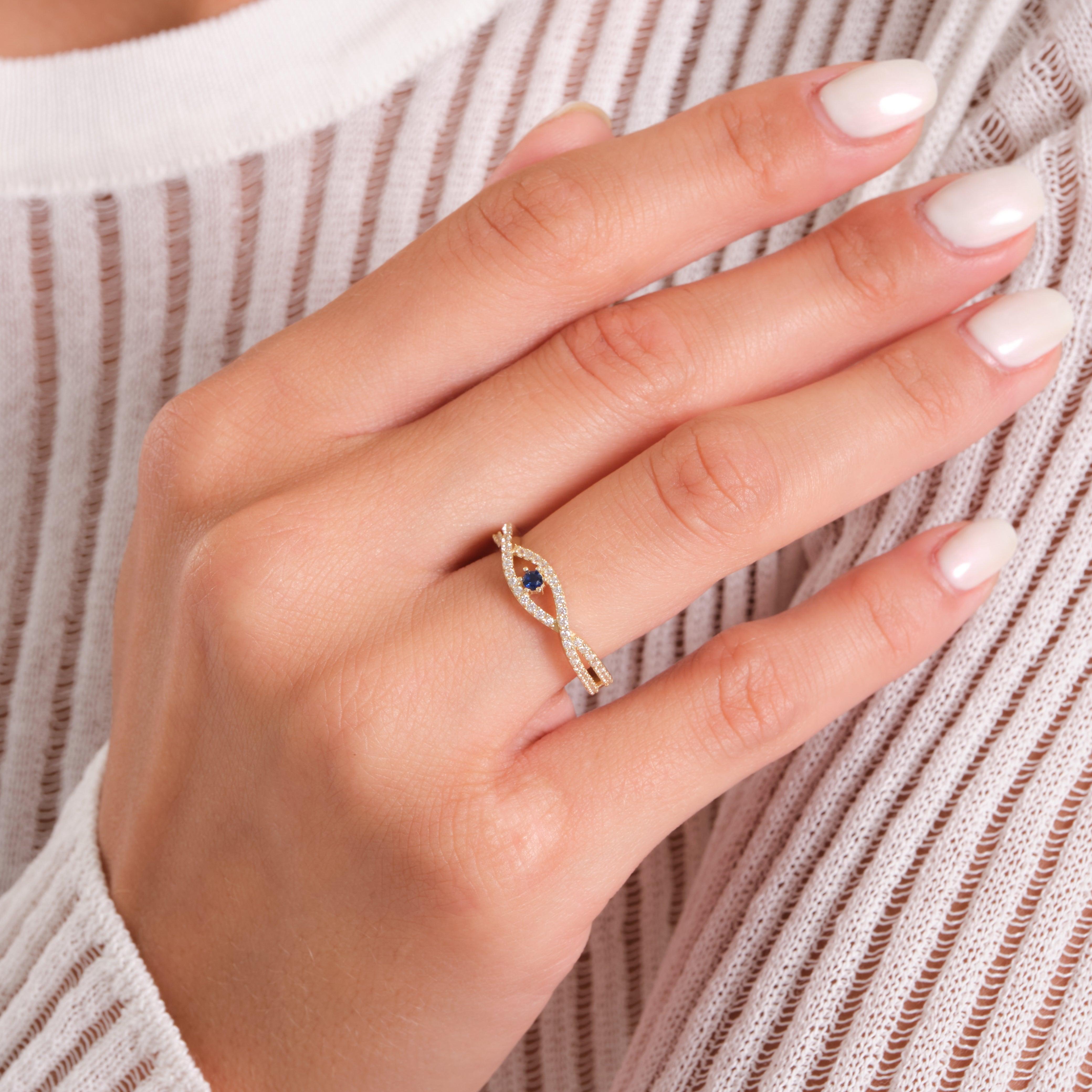 Gold ring with blue gemstone and twisted design on hand, elegant jewelry close-up