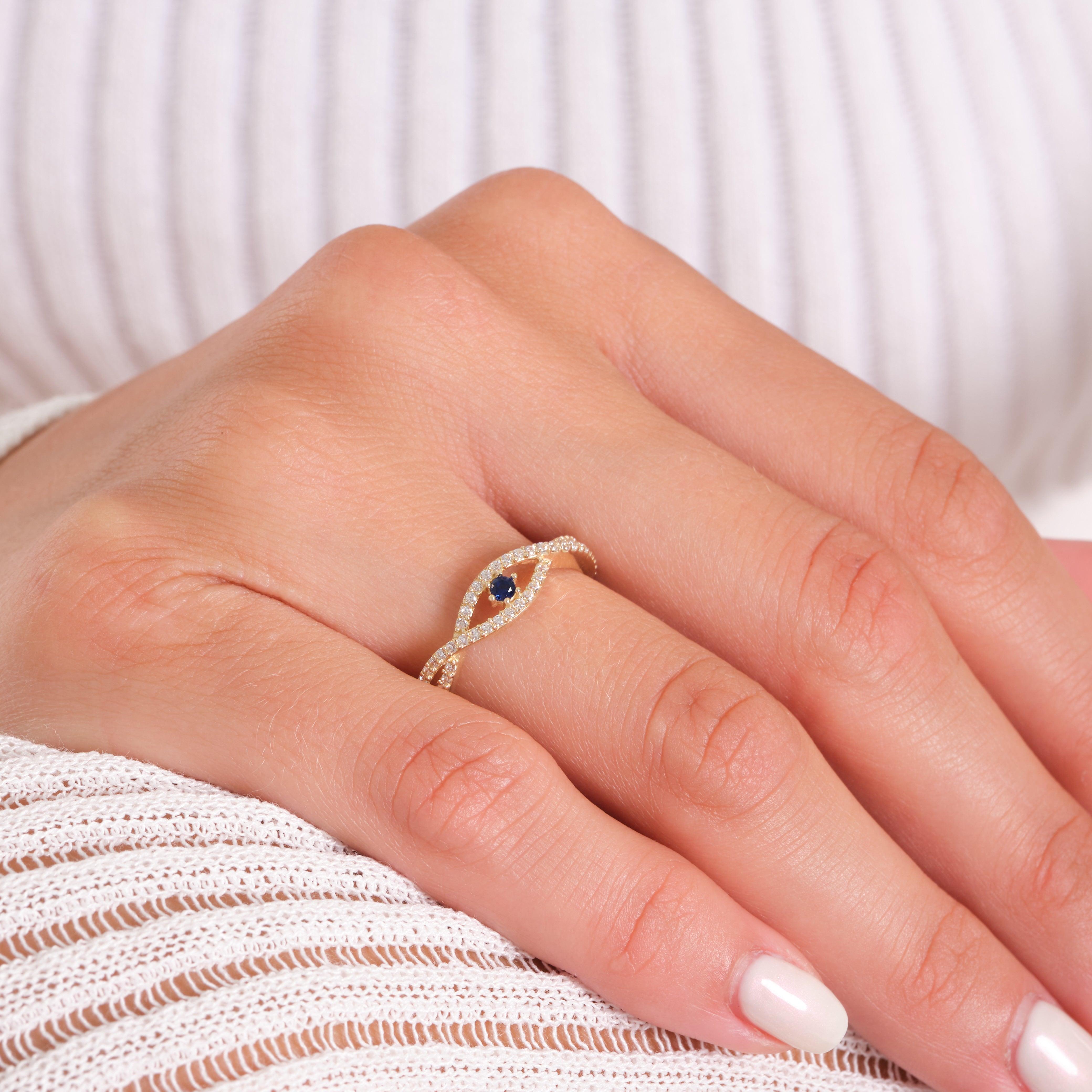 Gold ring with blue gemstone and diamond accents on woman's hand