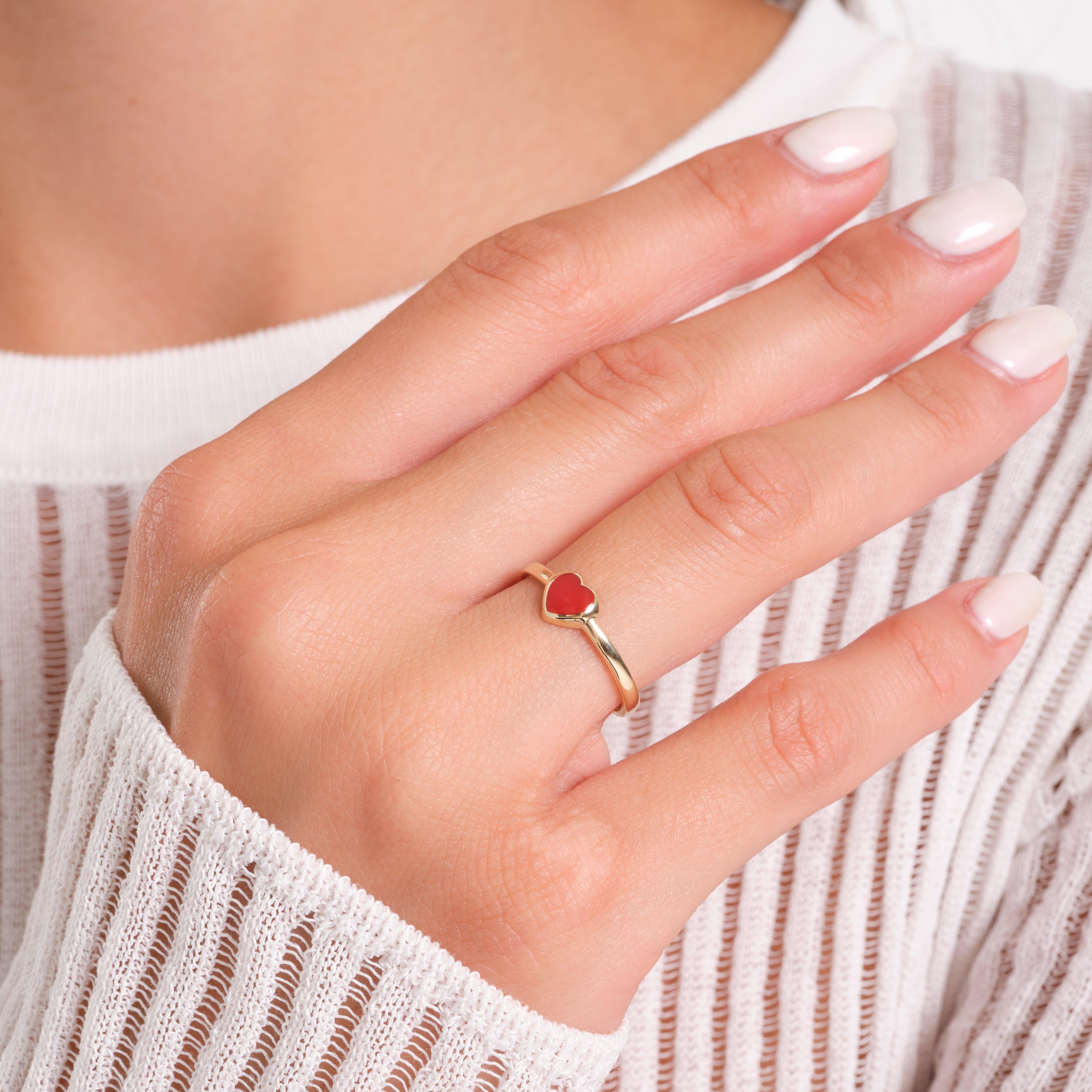 Gold ring with red heart-shaped stone on woman's hand, minimalist gold jewelry