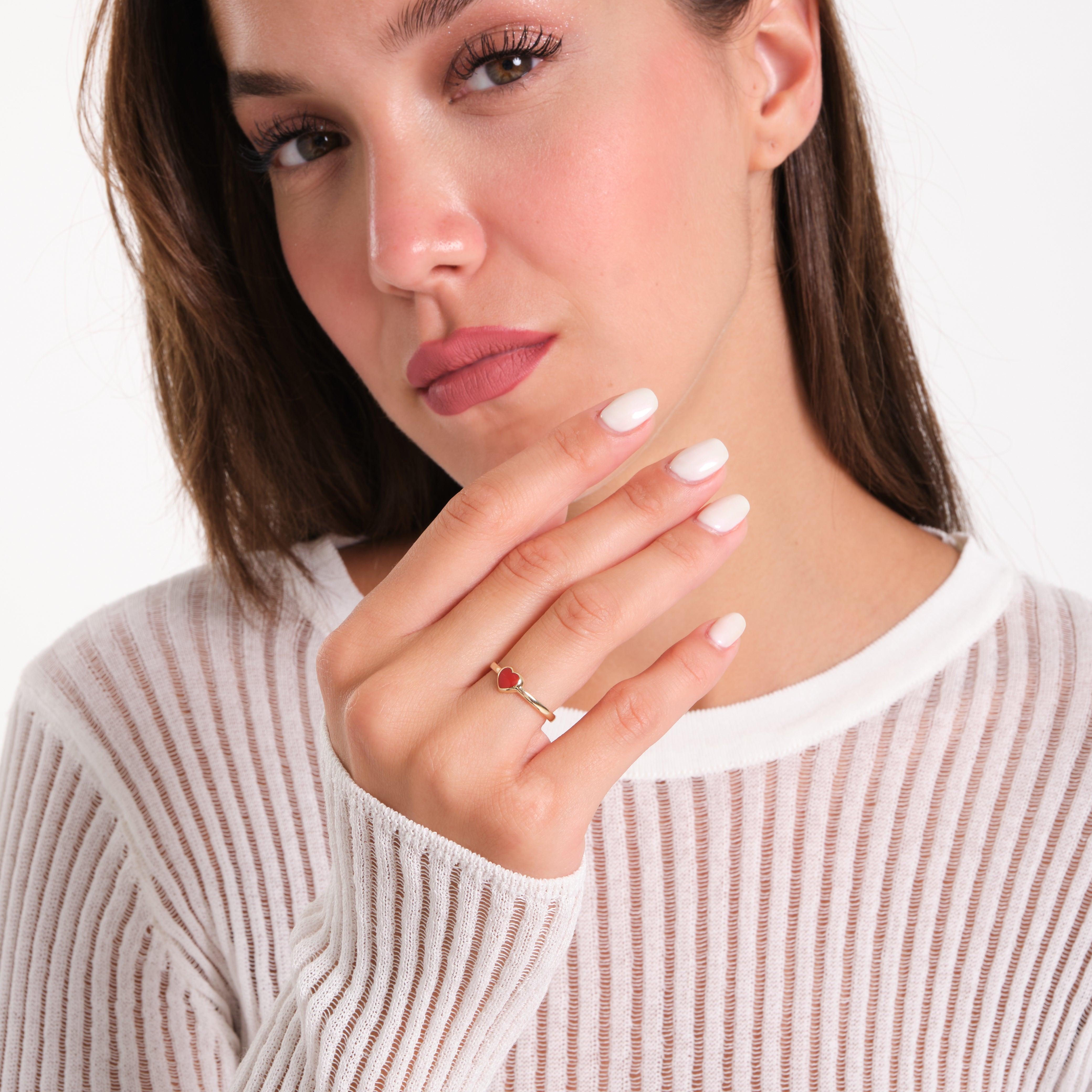 Woman wearing a gold ring with red gemstone, showcasing jewelry on her hand