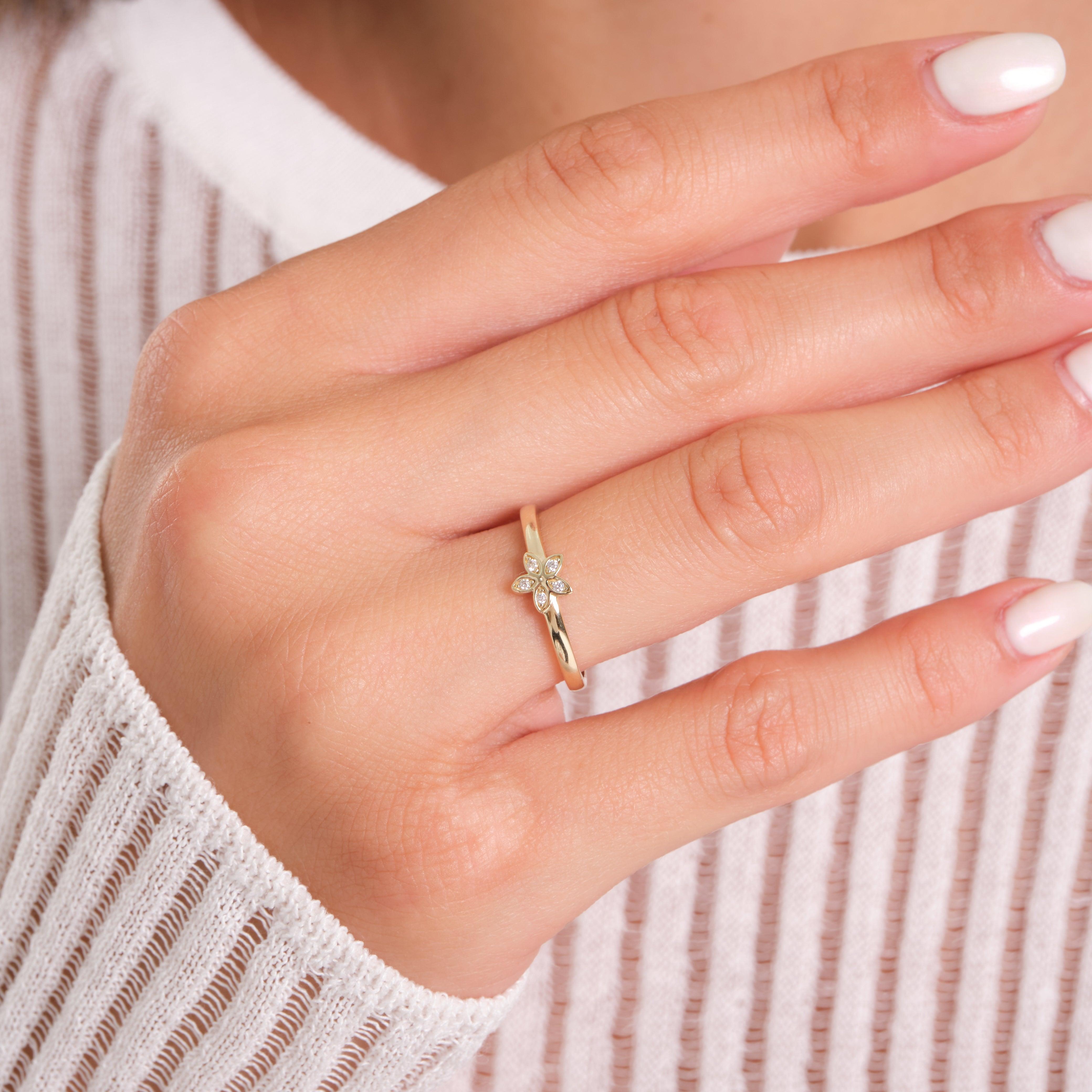 Gold flower diamond ring on woman's hand, delicate fine jewelry, close-up
