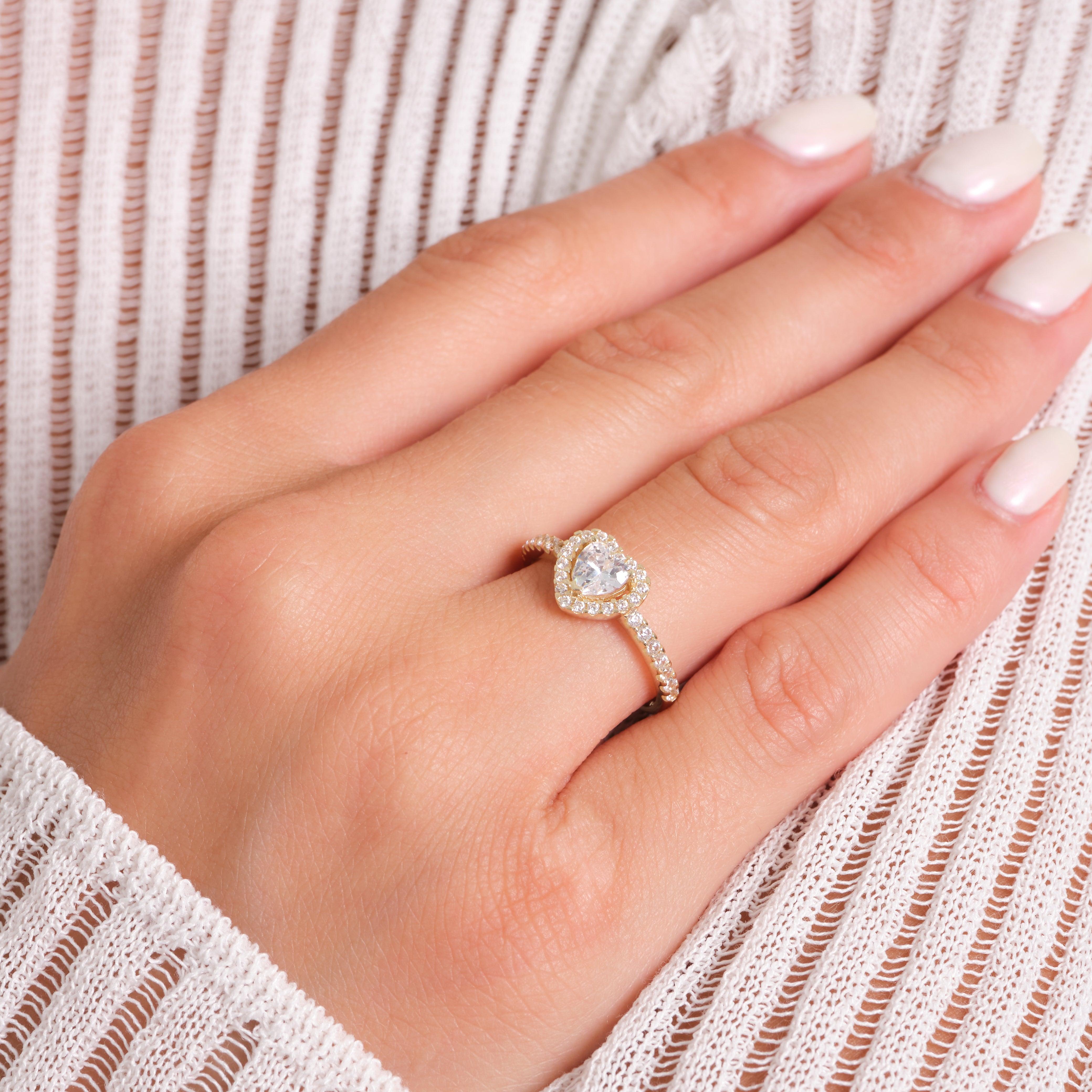 Gold heart-shaped diamond ring with pavé band on woman's hand