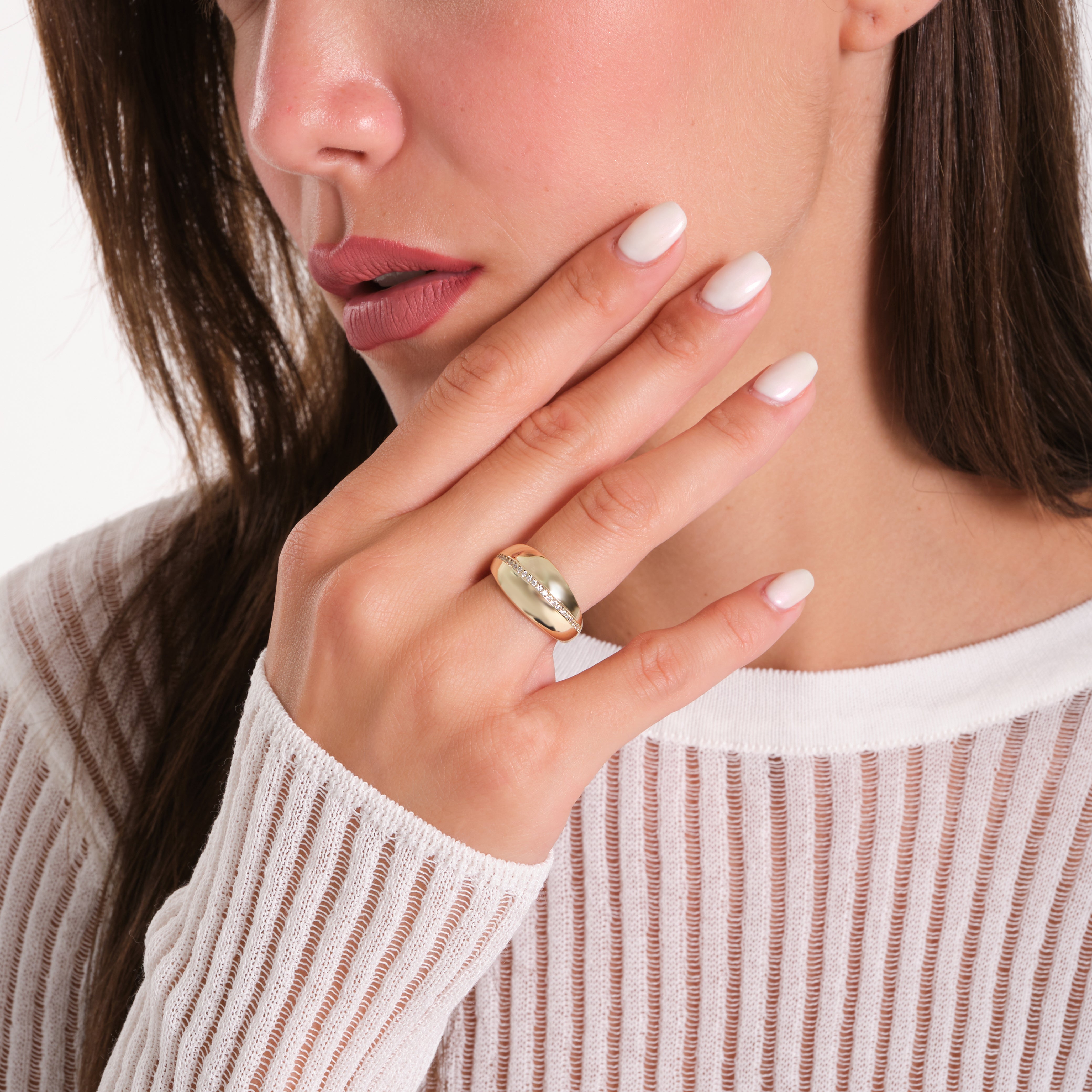 Close-up of a woman wearing a gold ring on her finger with a neutral background