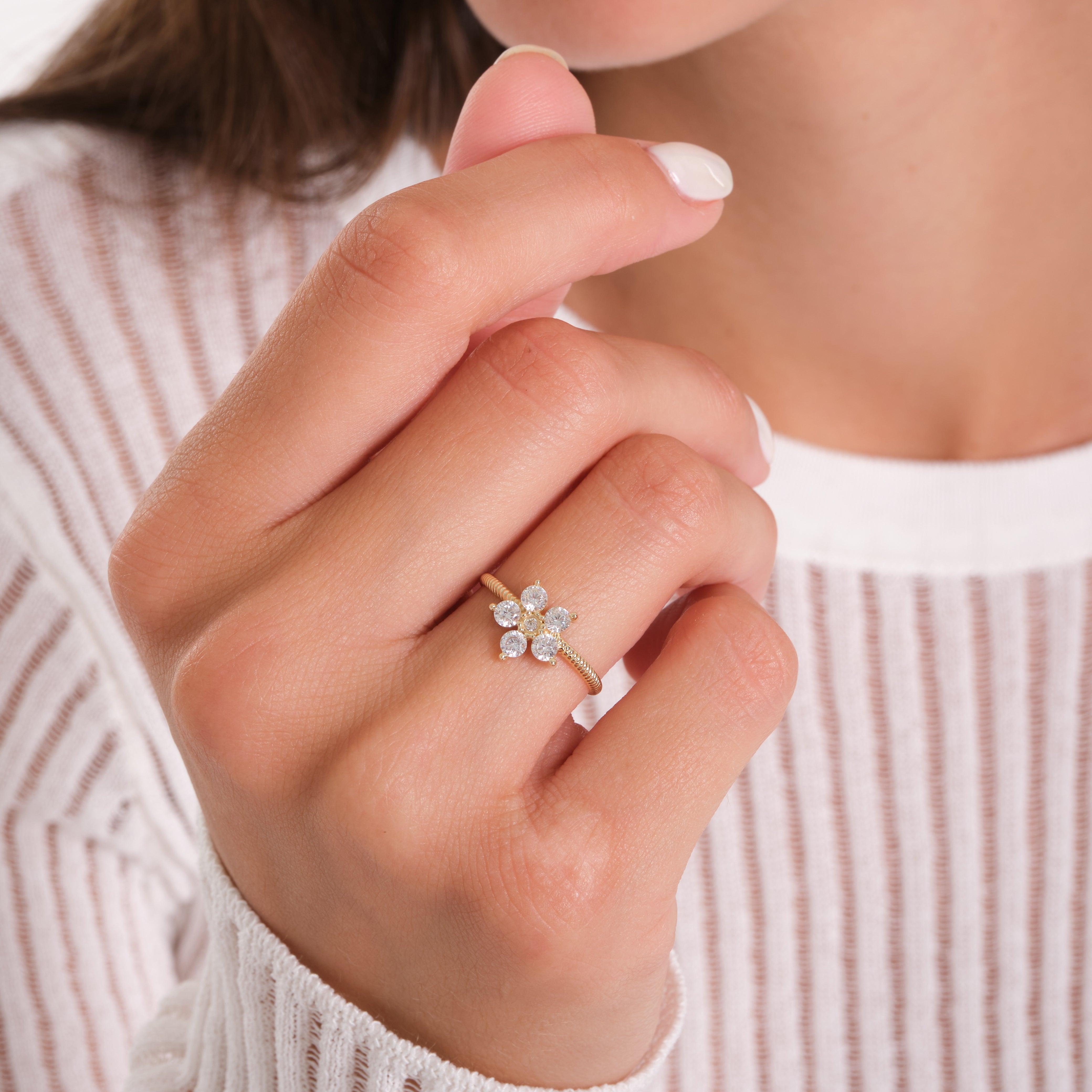 Gold flower-shaped diamond ring on woman's finger, close-up jewelry detail