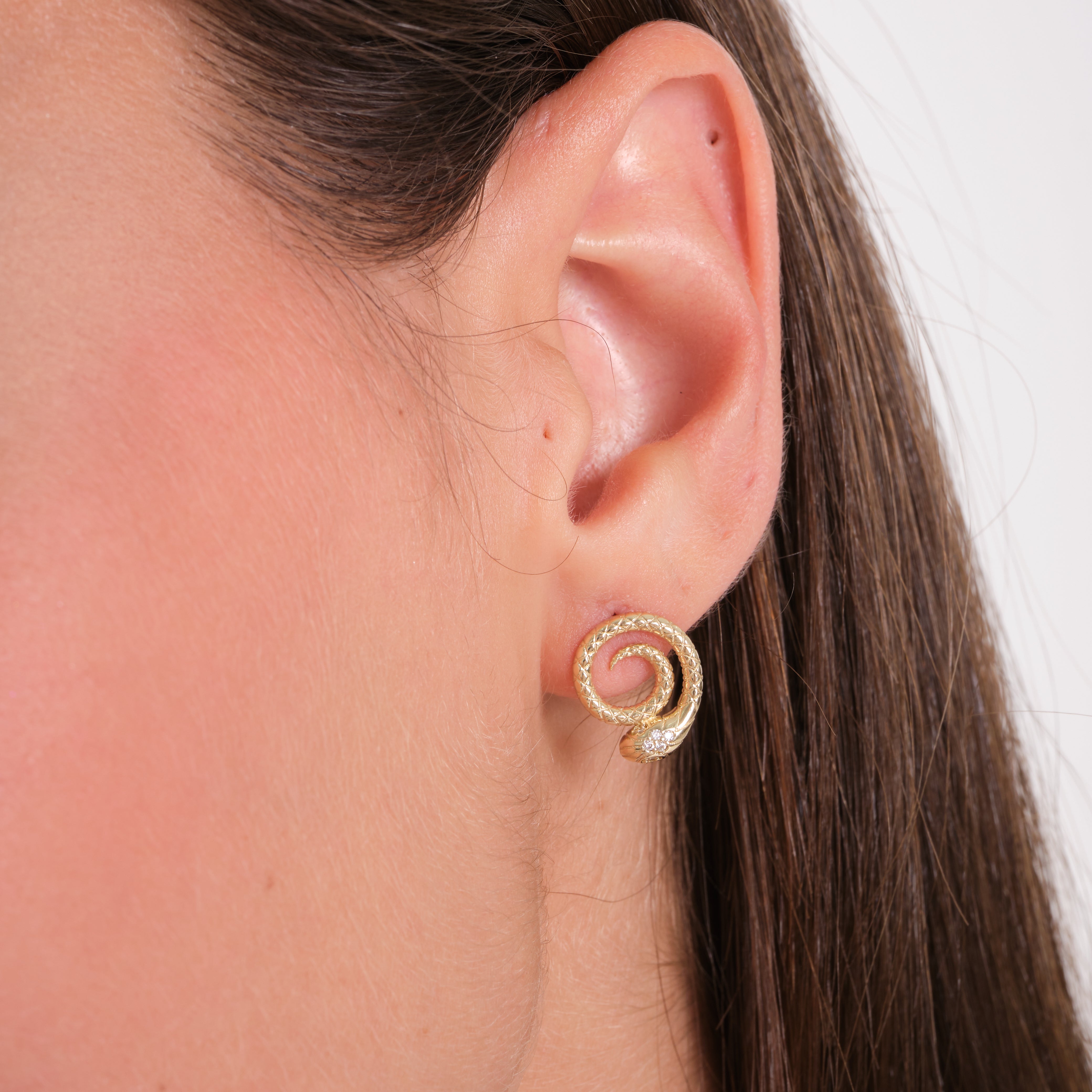 Gold spiral earring worn by a person with a neutral background