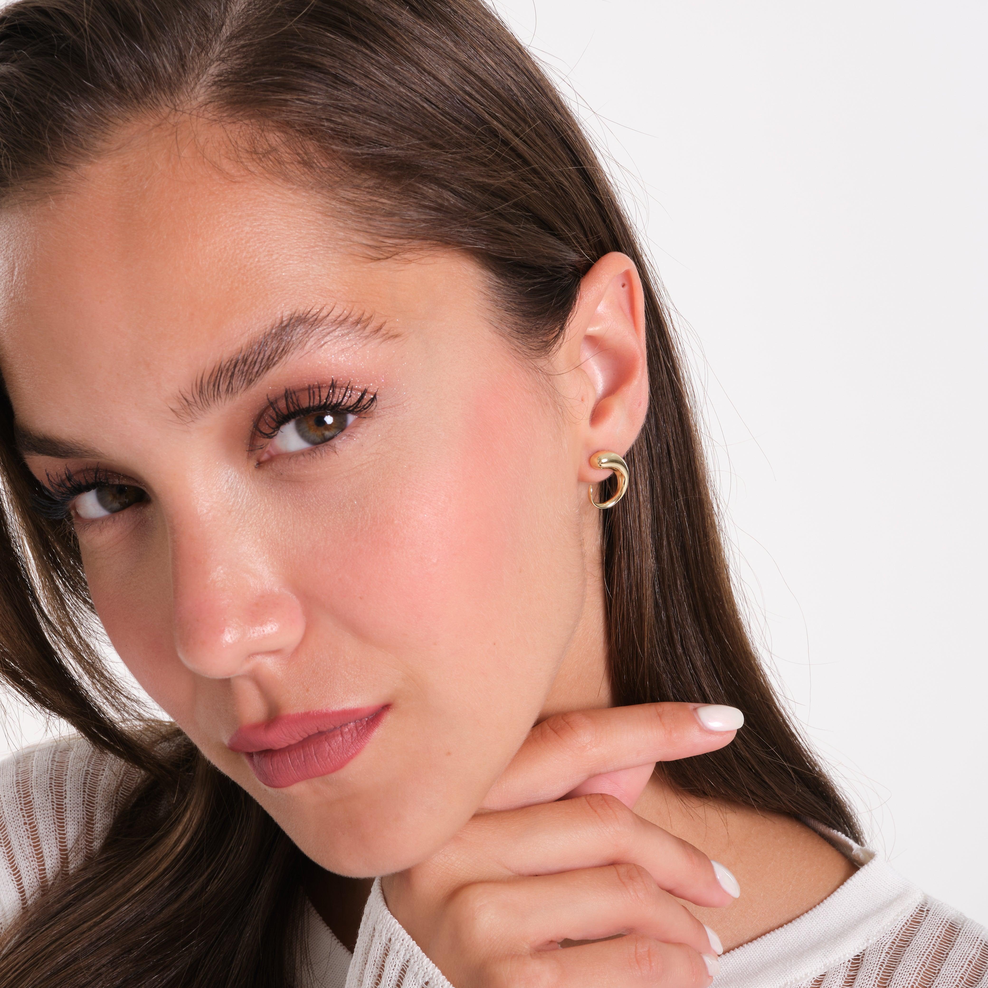 Woman wearing minimalist gold hoop earrings, close-up on ear and face