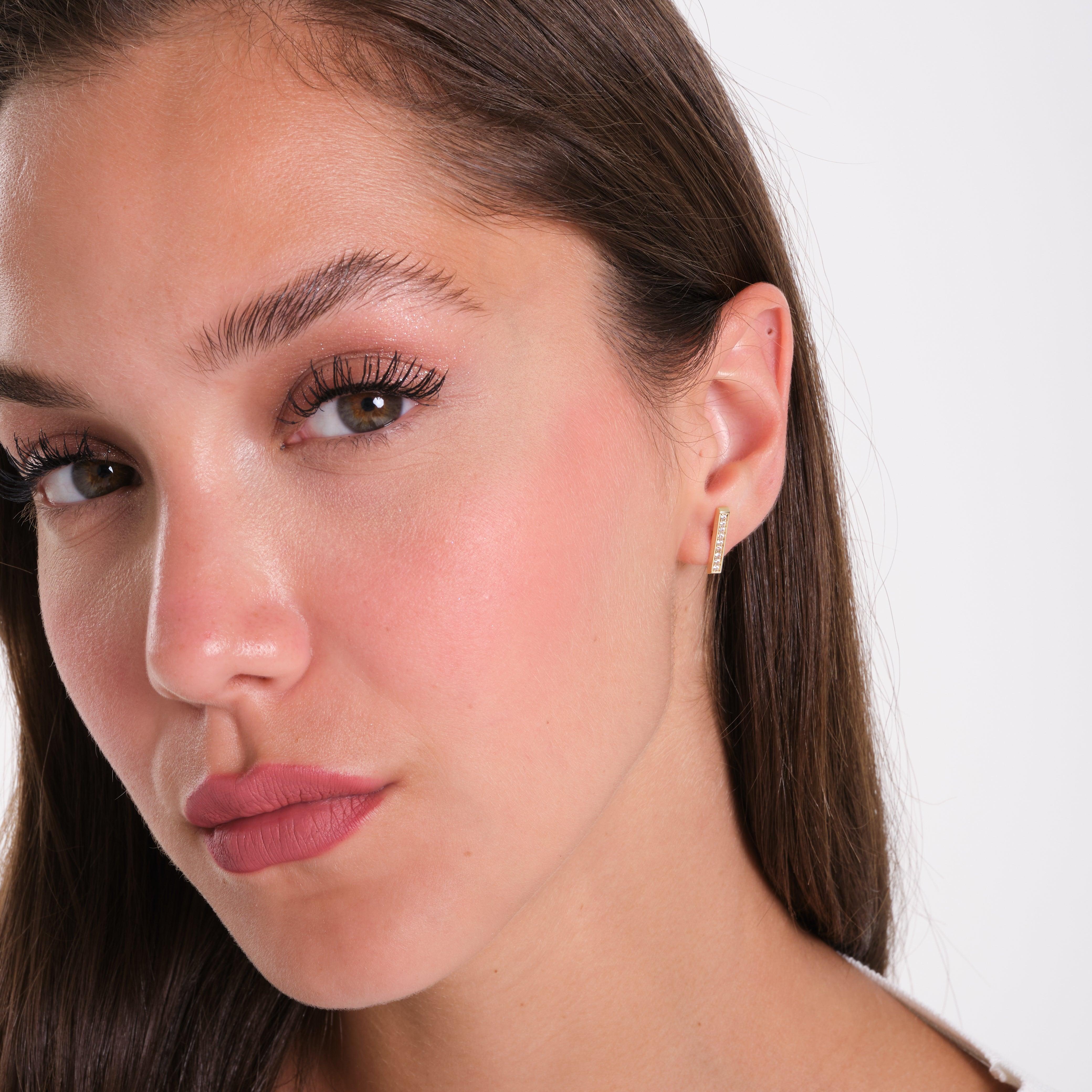 Woman wearing a minimalist gold earring with small gemstones, close-up view