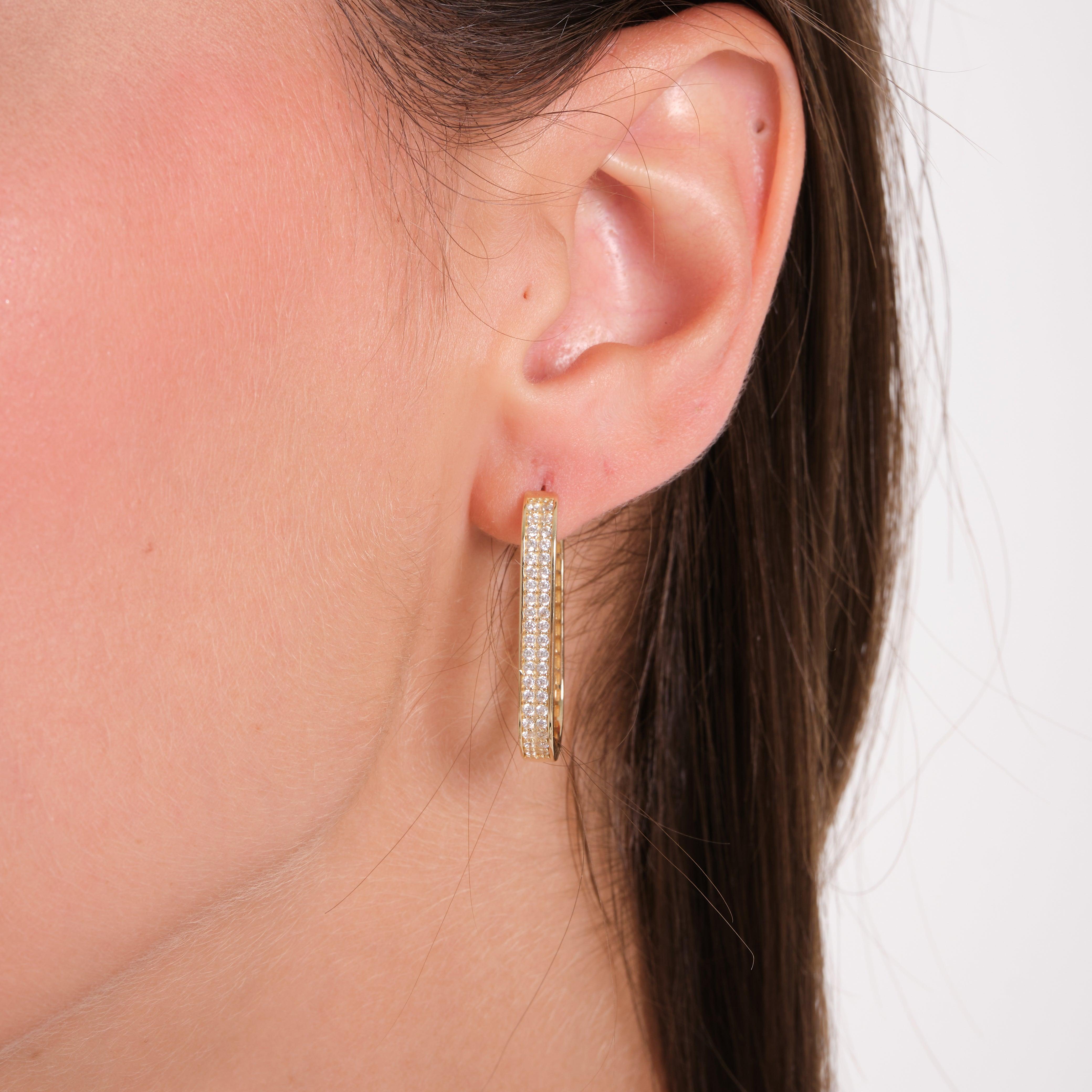 Close-up of a gold hoop earring with pavé stones worn on a woman's ear