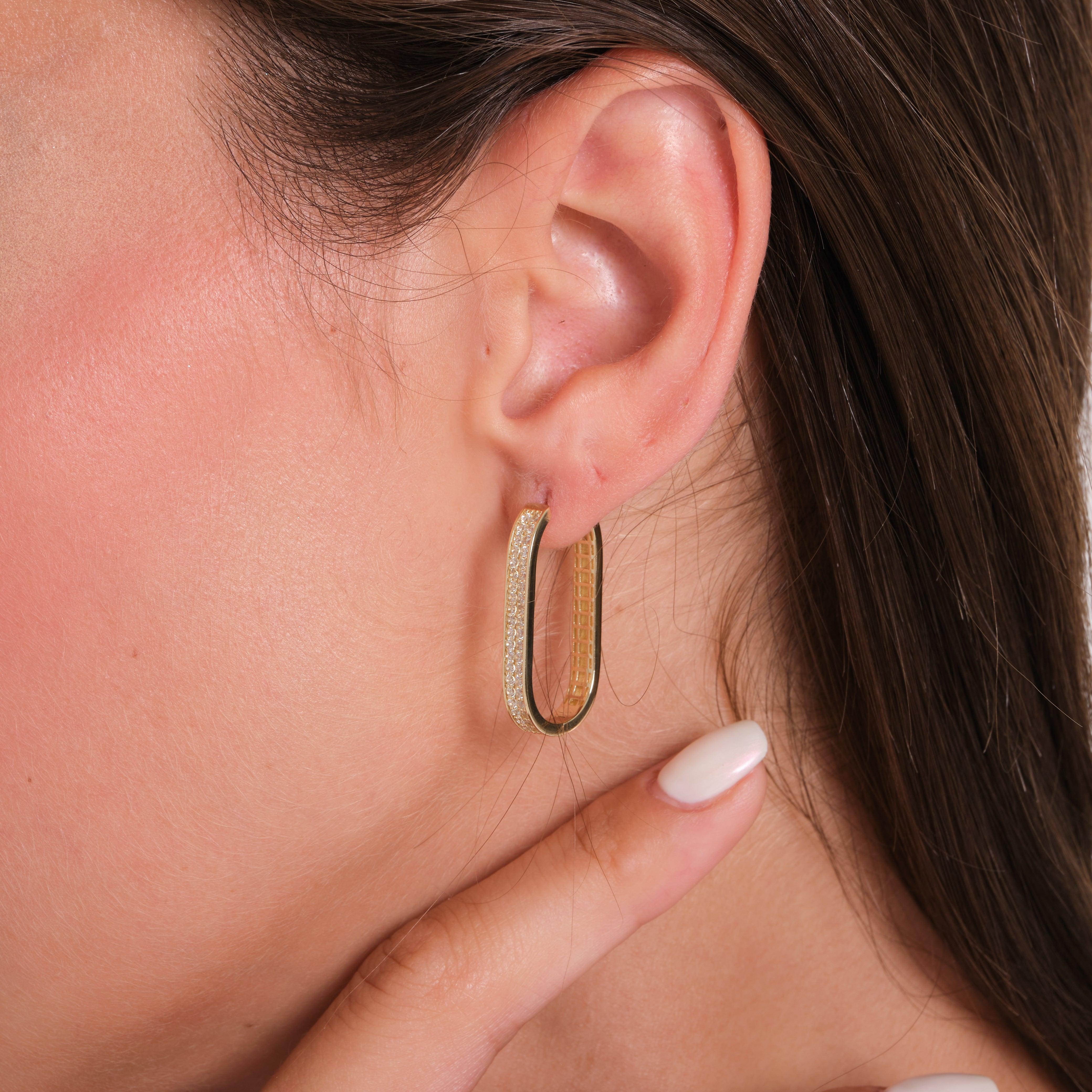 Rectangular gold hoop earring with textured surface on woman's ear