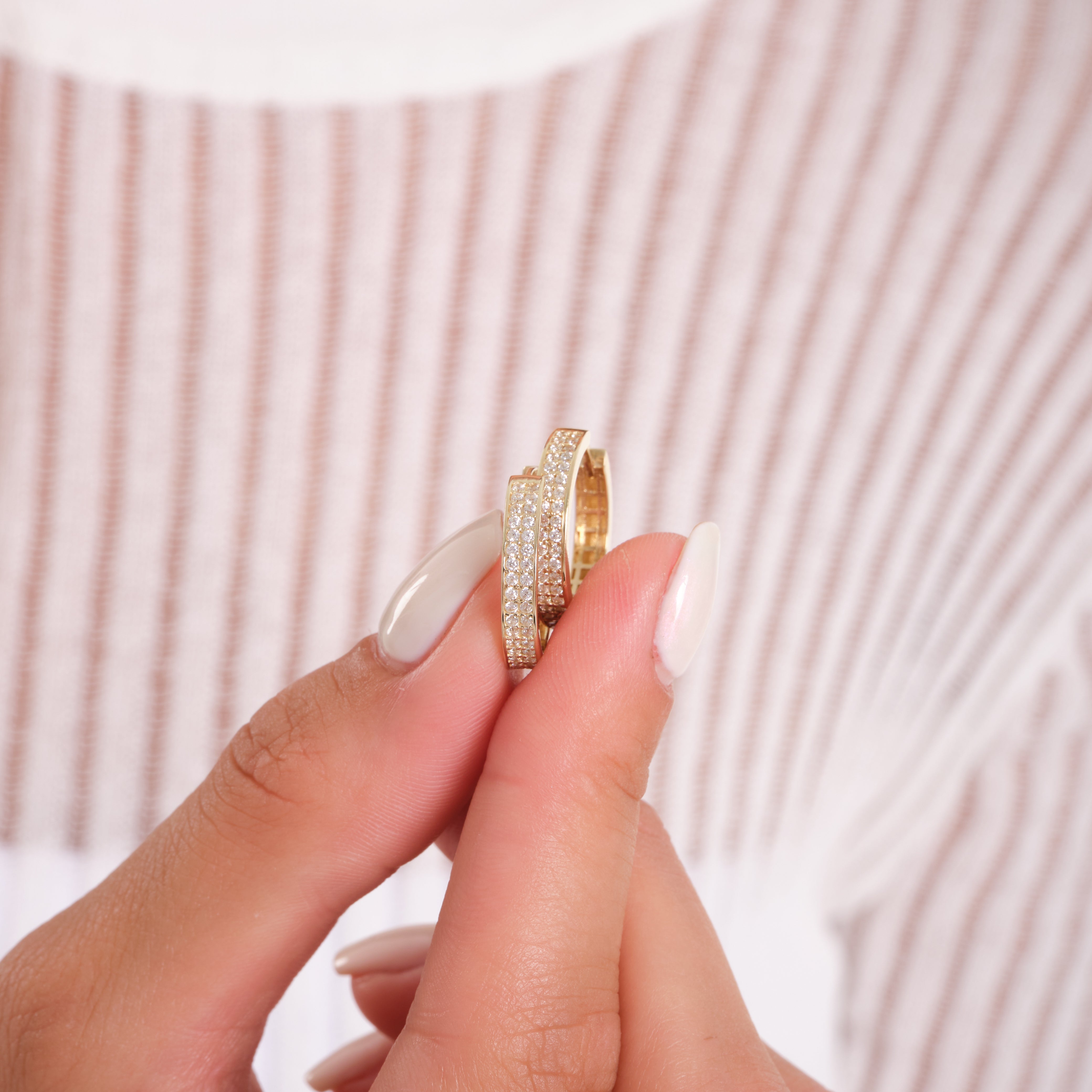 Gold ring with diamond accents held between fingers against a neutral background