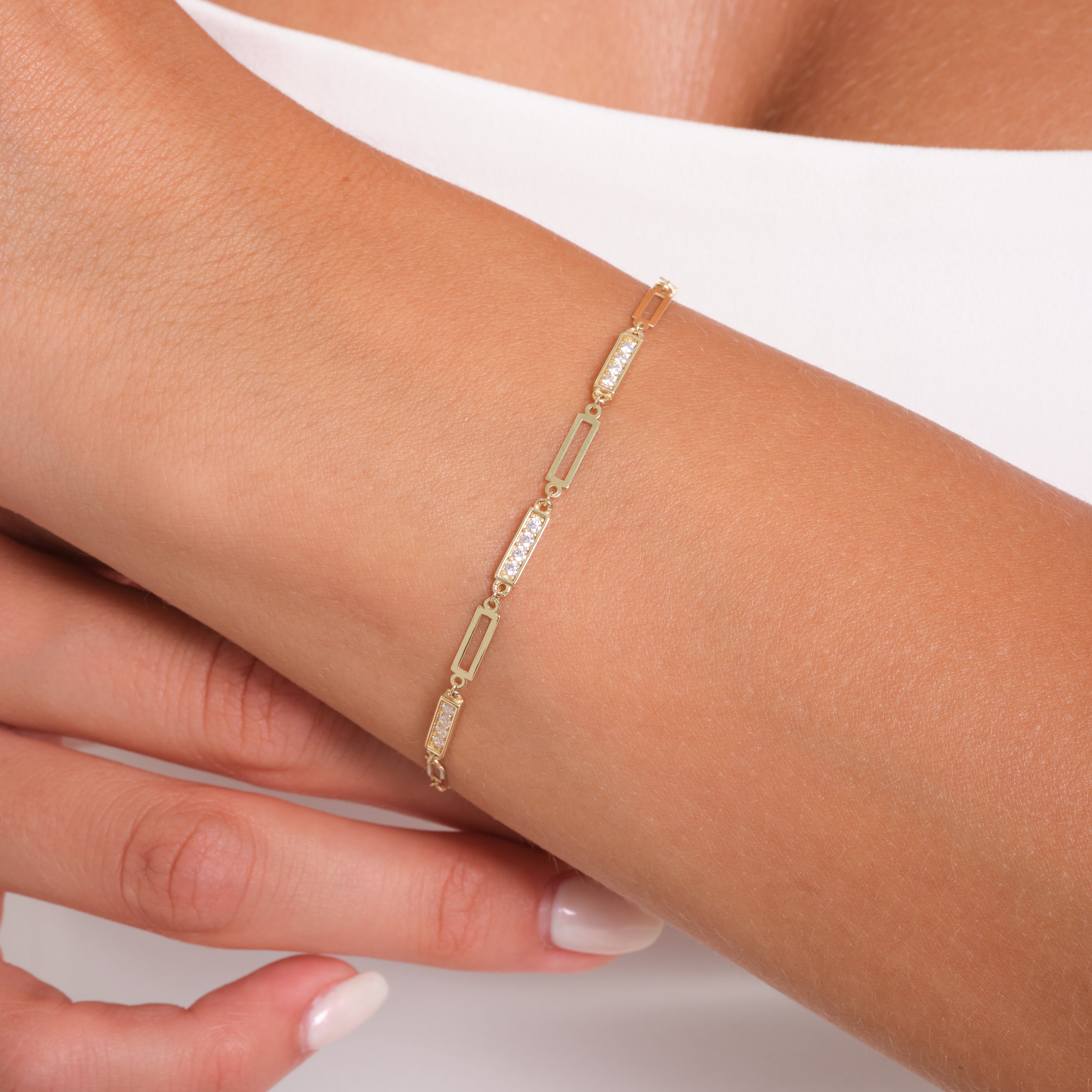 Gold bracelet with clear stones on a wrist against a white background