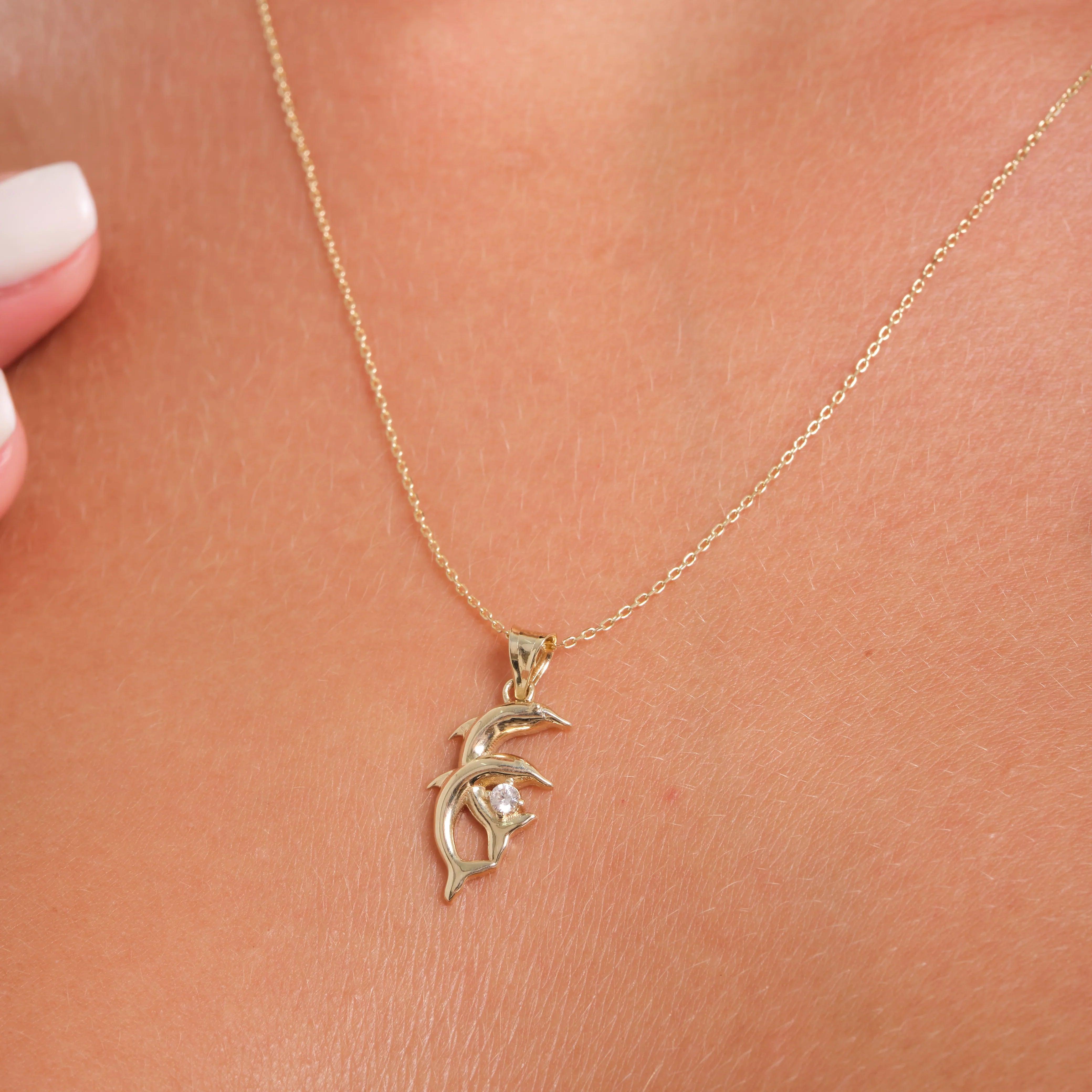 Gold dolphin pendant necklace with gemstone on woman's neck