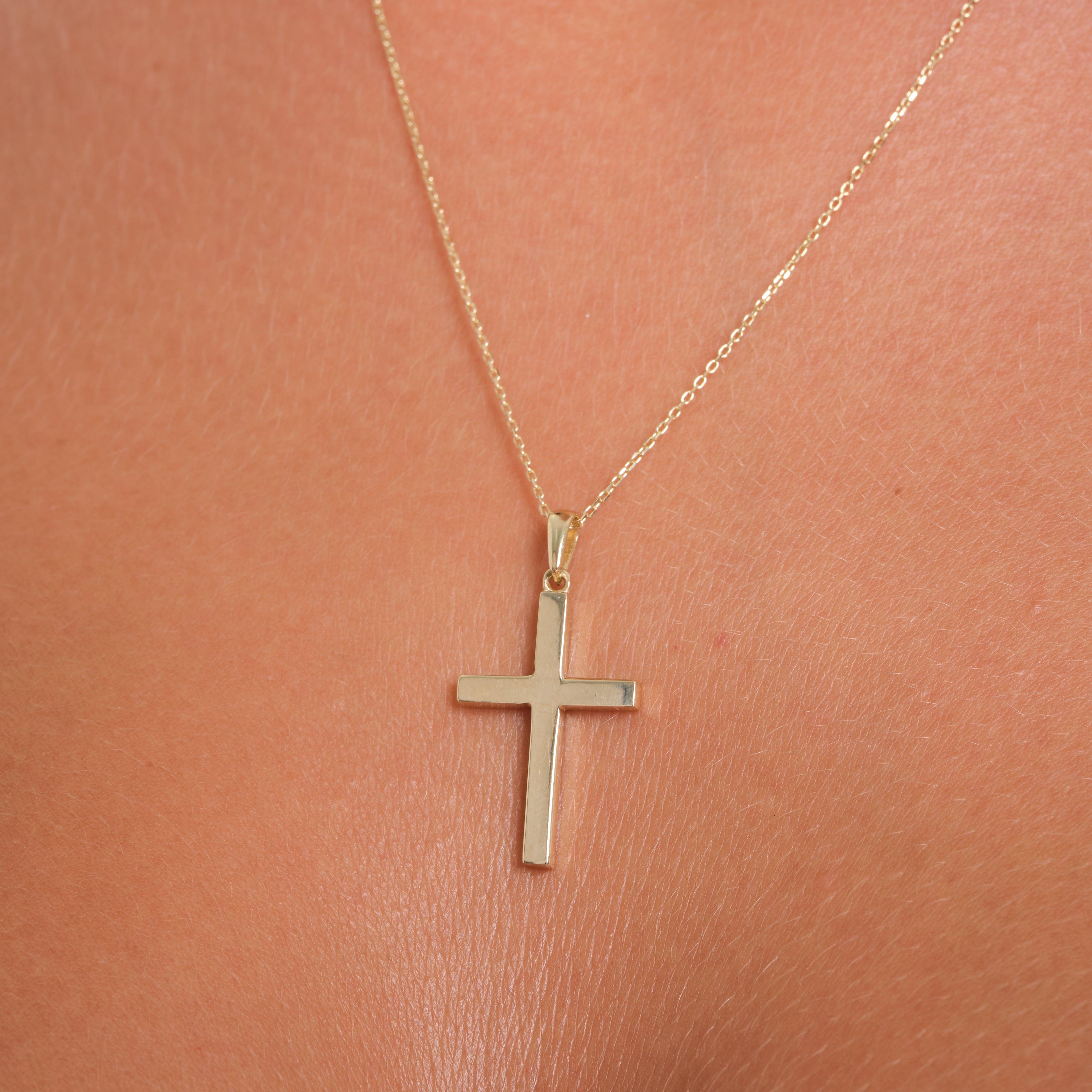 Gold cross pendant necklace on skin, fine gold jewelry close up