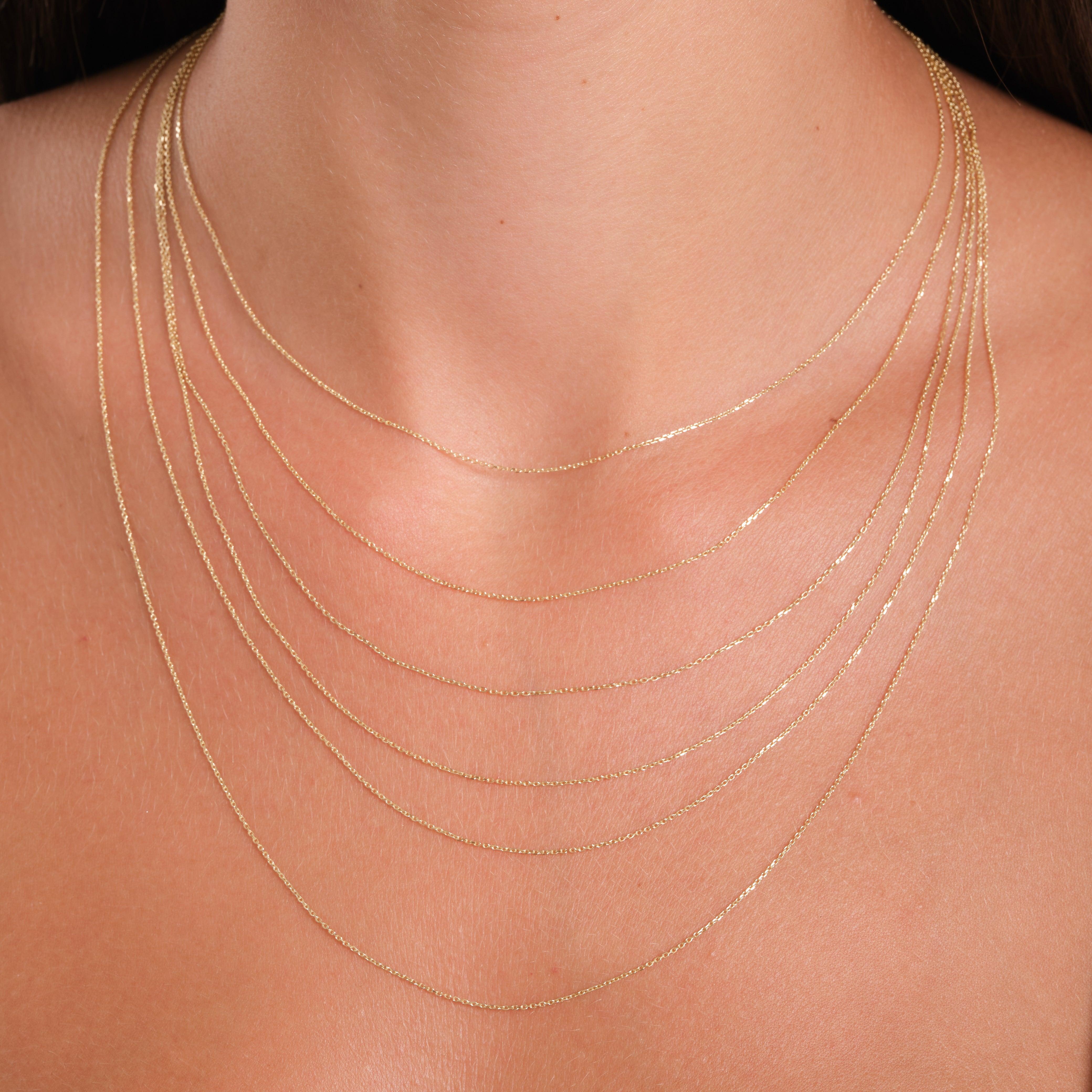 Layered delicate gold chain necklaces on woman's neck, fine jewelry close-up